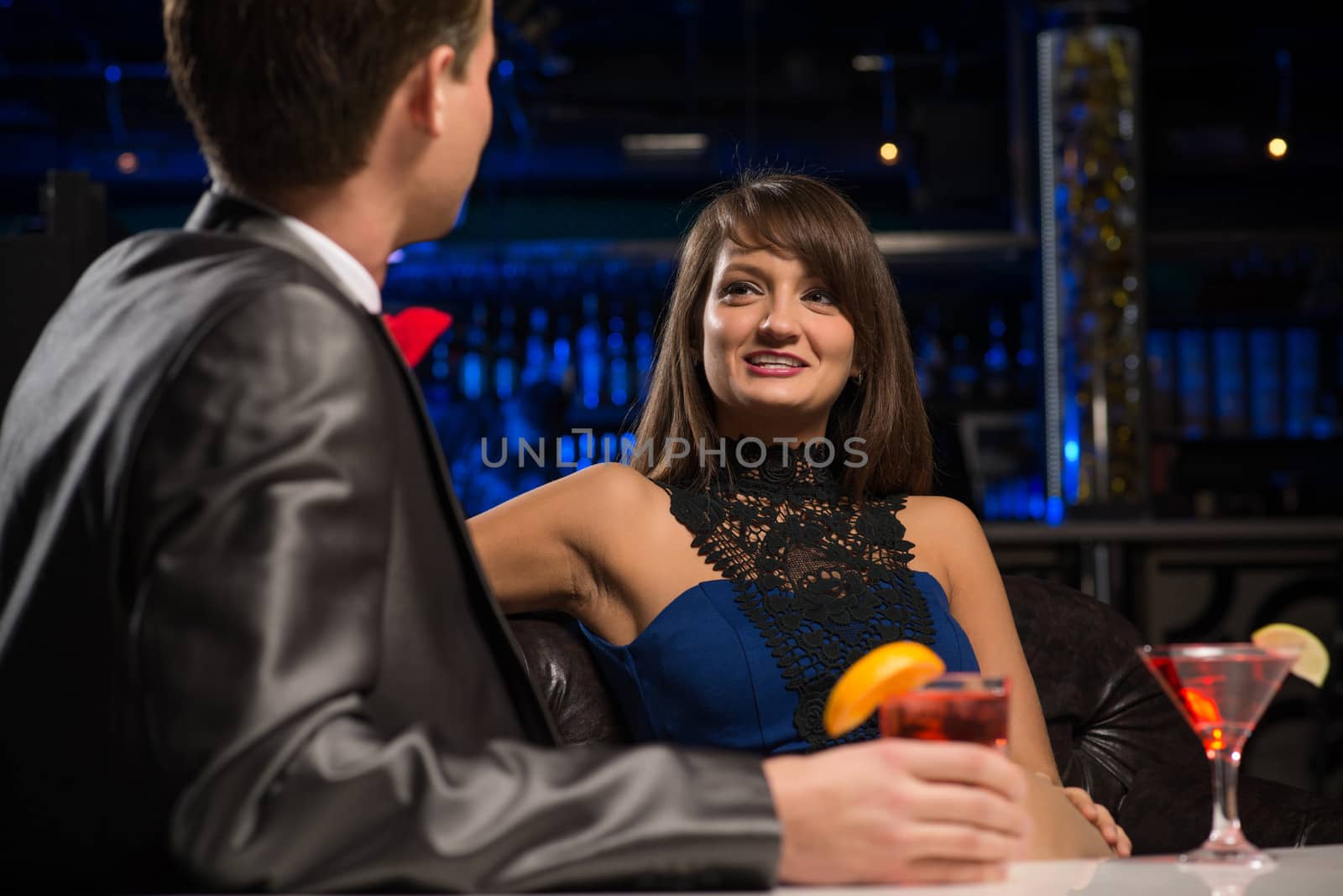 portrait of a woman in a nightclub, sitting on the couch and talking with man