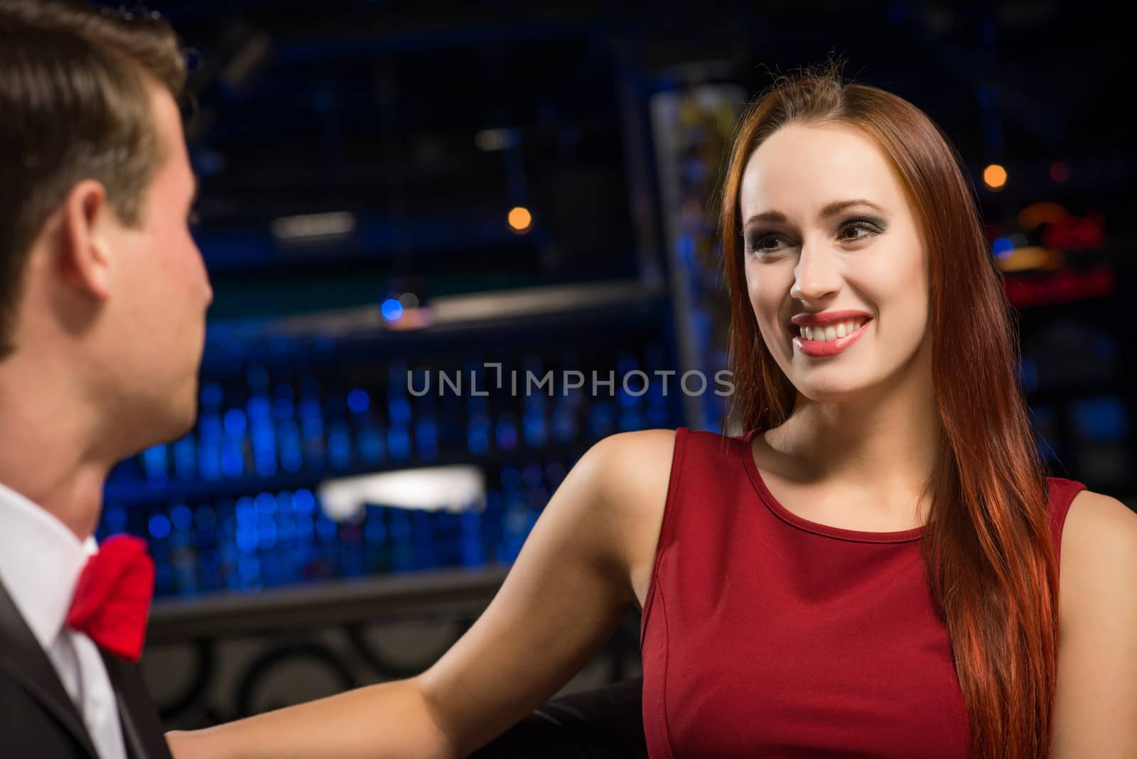 portrait of a woman in a nightclub, sitting on the couch and talking with man