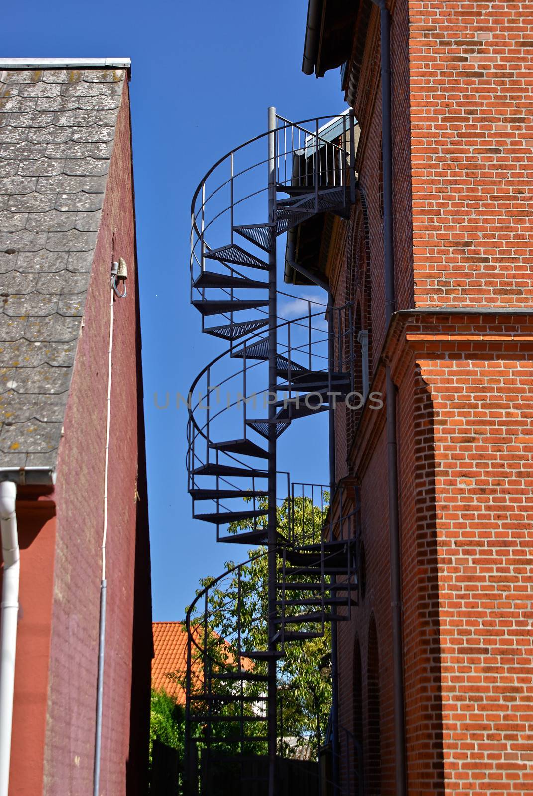 Metal modern spiral staircase between two old buildings