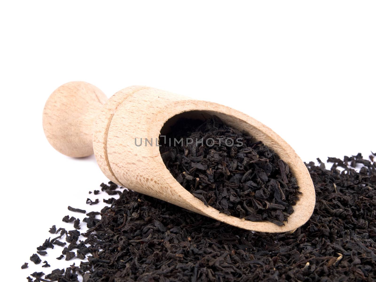 Picture of dry aromatic black tea leafs and wooden shovel on white background