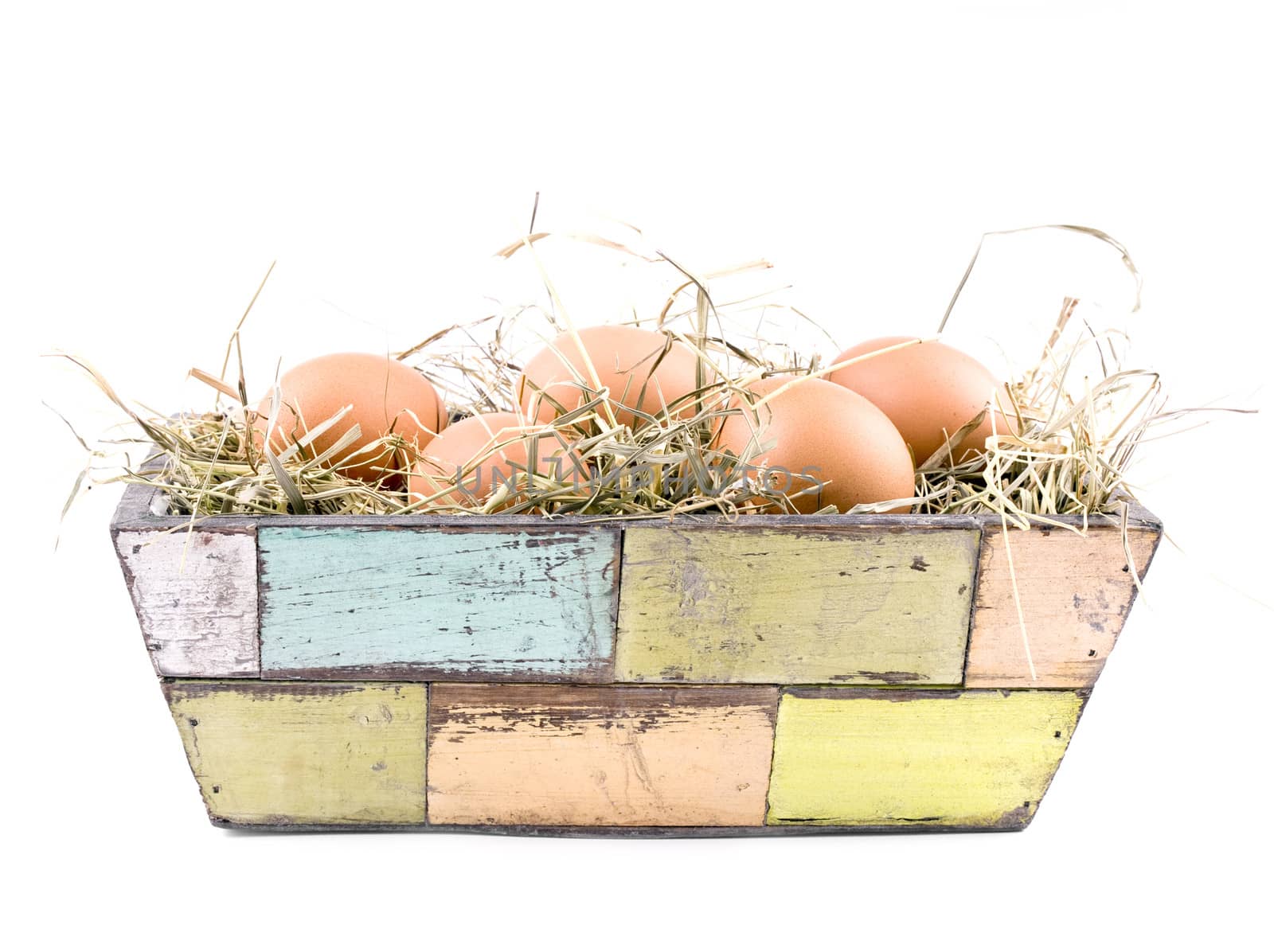 Five fresh eggs in old-fashioned flowerpot filled with hay on white background