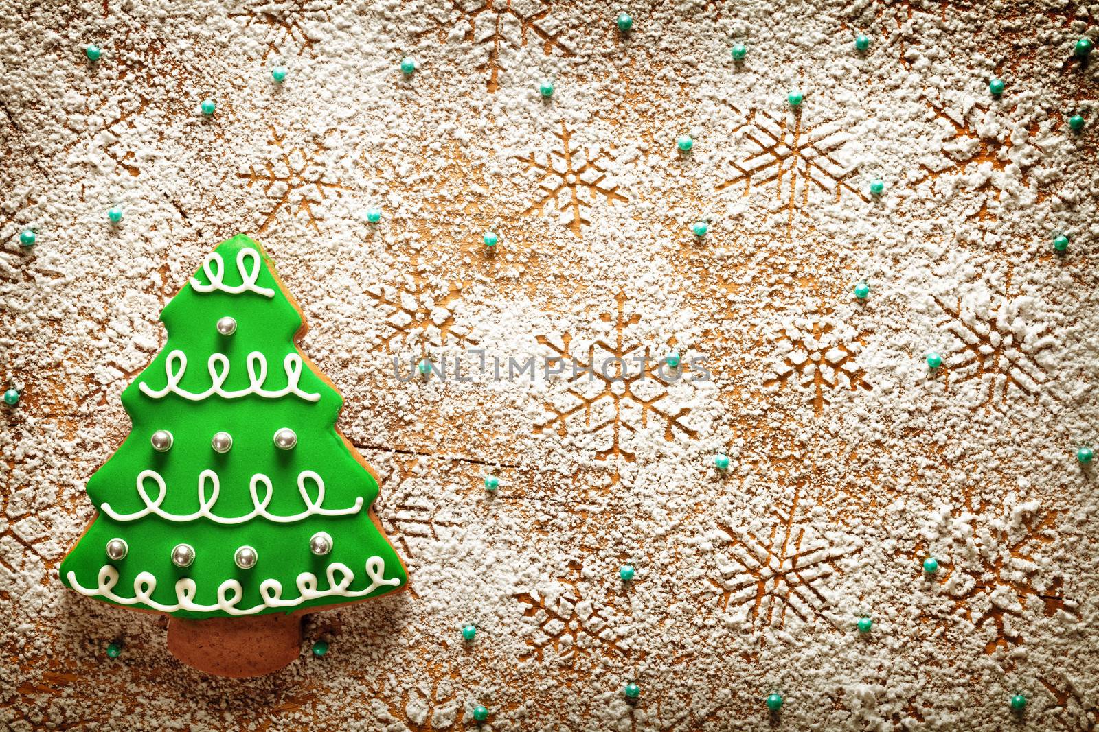 Christmas background. Gingerbread tree and snowflakes made of icing sugar on wooden table. Top view