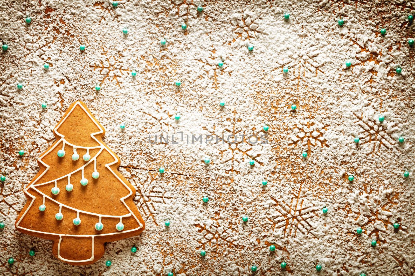 Christmas background. Gingerbread tree and snowflakes made of icing sugar on wooden table. Top view