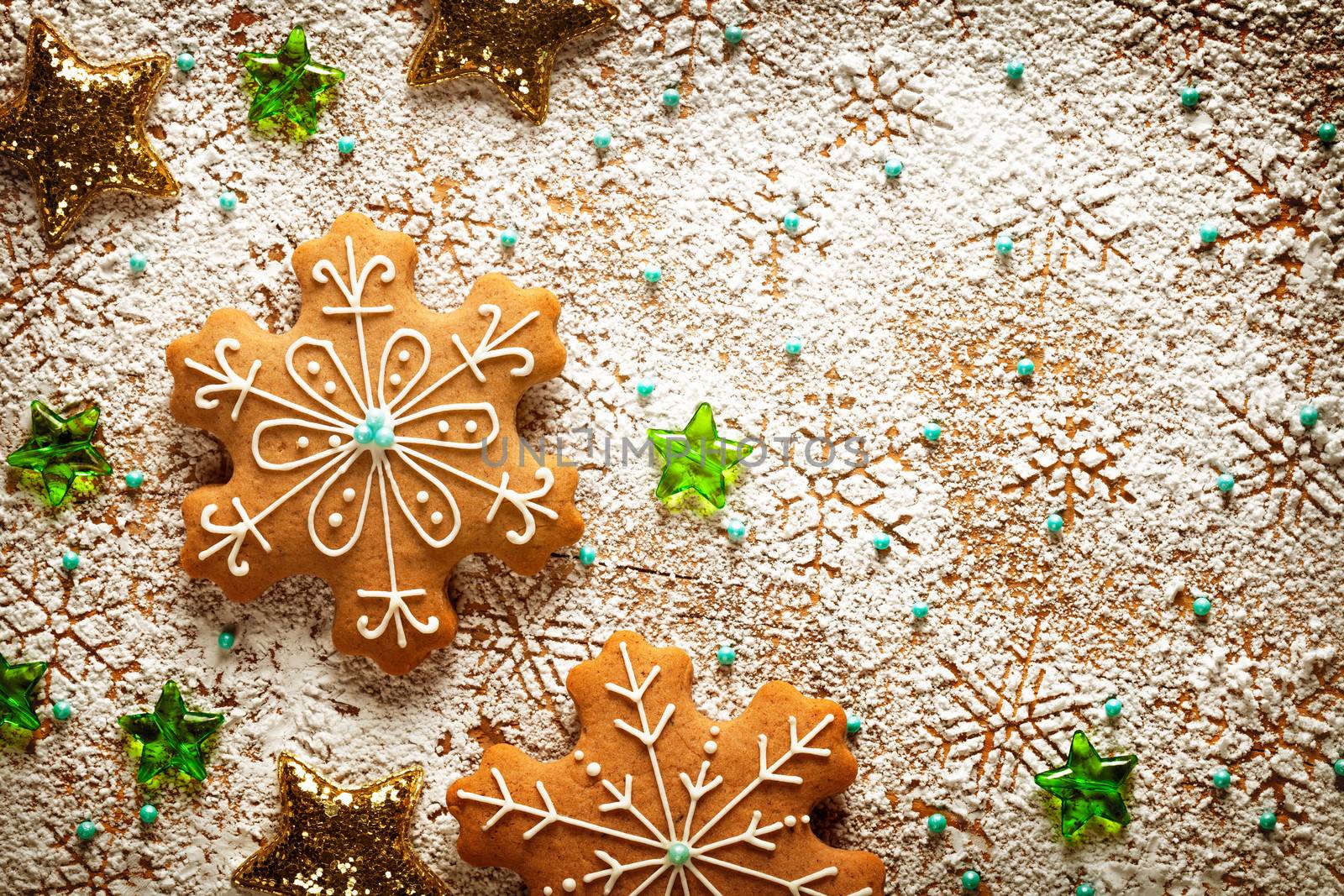 Christmas gingerbreads on snowflakes background made of icing sugar on wooden table. Top view