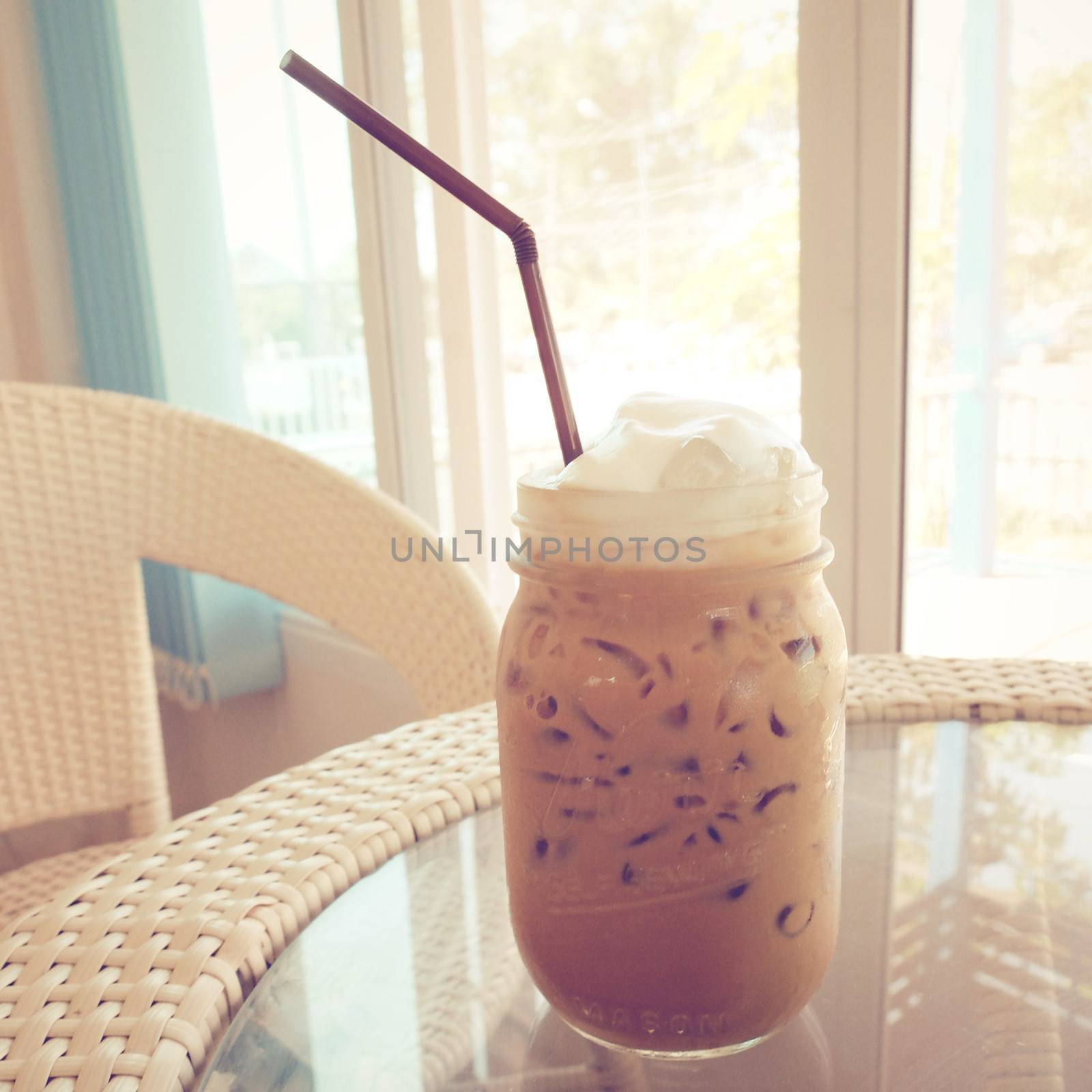 Iced coffee and straw on table with retro filter effect by nuchylee