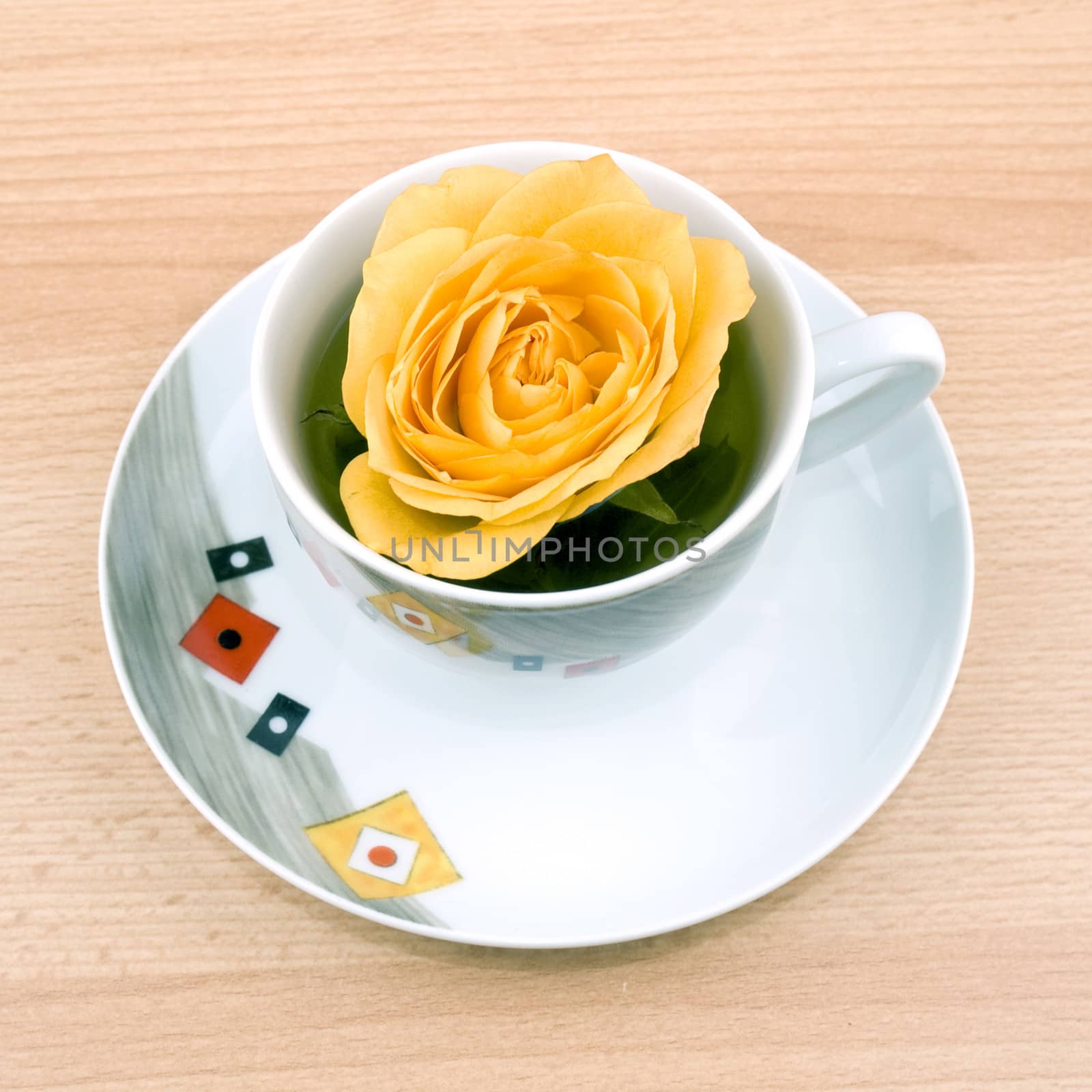 Cup of aromatic green tea with single rose on wooden table