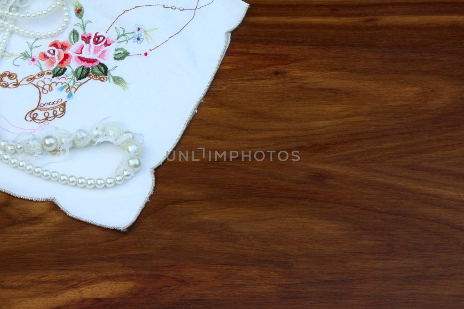 Pearls on embroidered cloth over wooden table