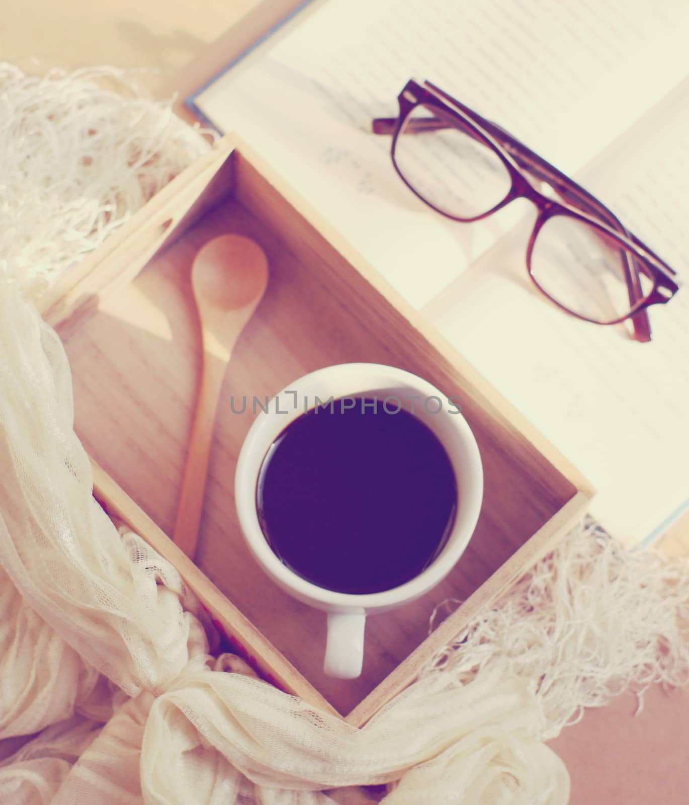 Eyeglasses and book with black coffee on wooden tray, retro filt by nuchylee