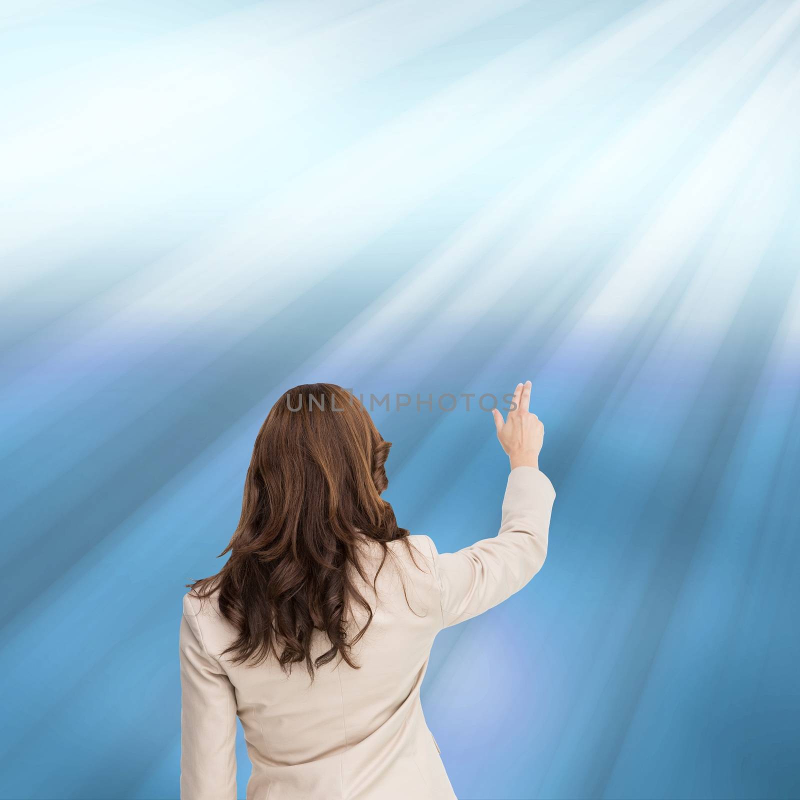 Composite image of brunette businesswoman standing back to camera pointing at something on blue shining background
