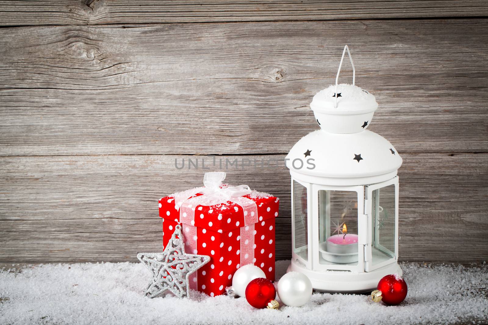 Burning lantern in the snow with christmas decoration, on wood background,