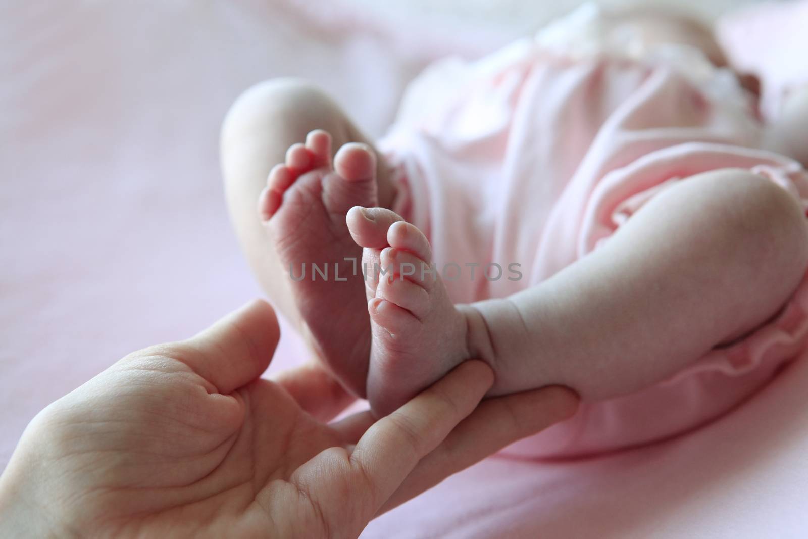 Parent hand hold baby girl legs