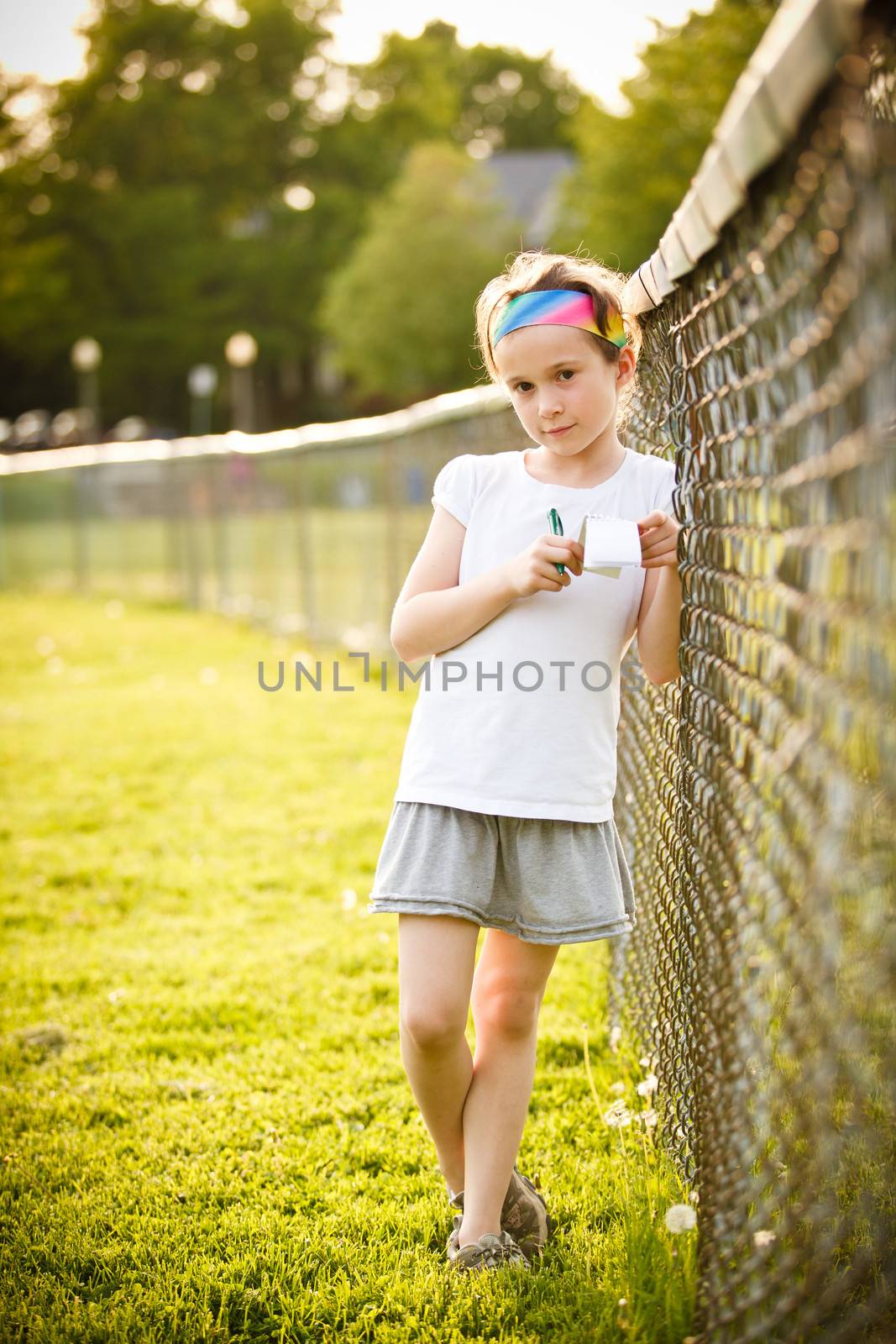 Little girl writing outside on the grass at the golden hour
