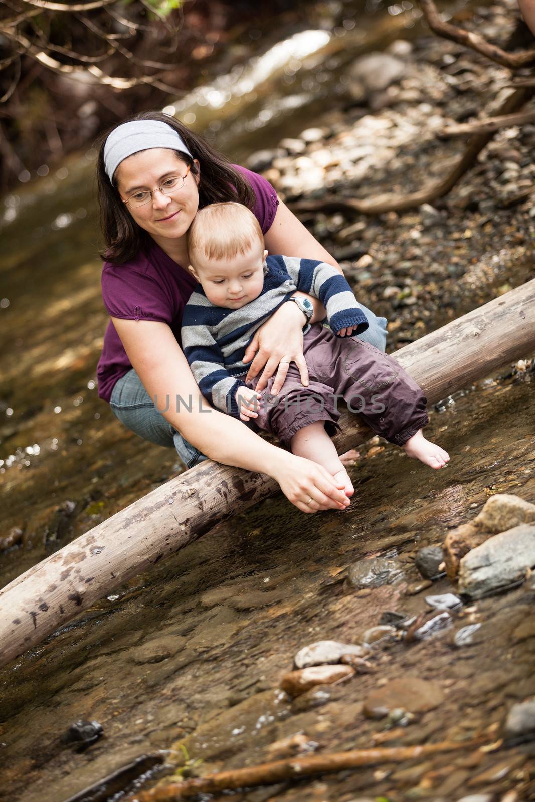 Mother and son playing on a tree trunk in a river