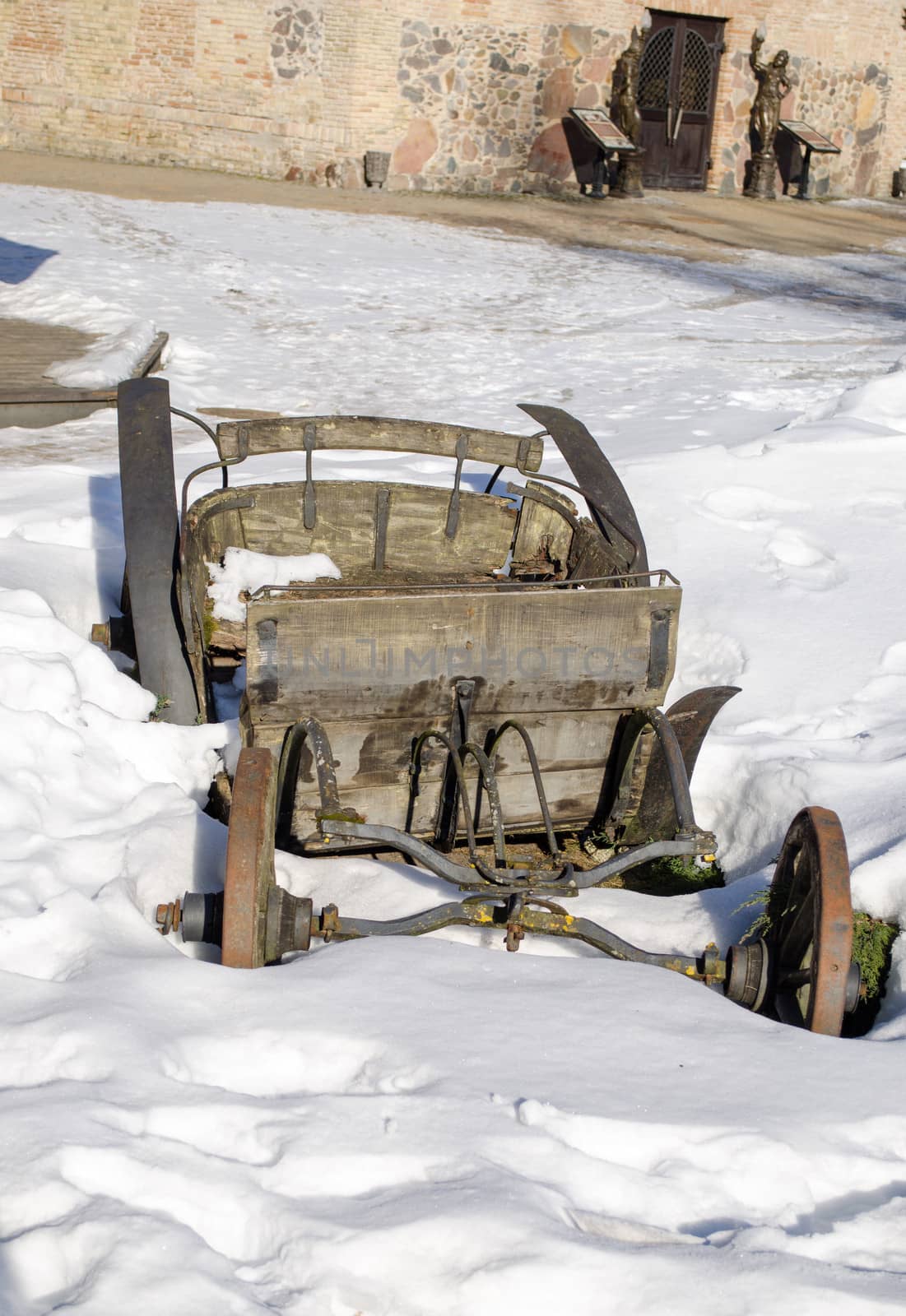 vintage grunge dirty wooden carriage remains covered with snow in winter park.