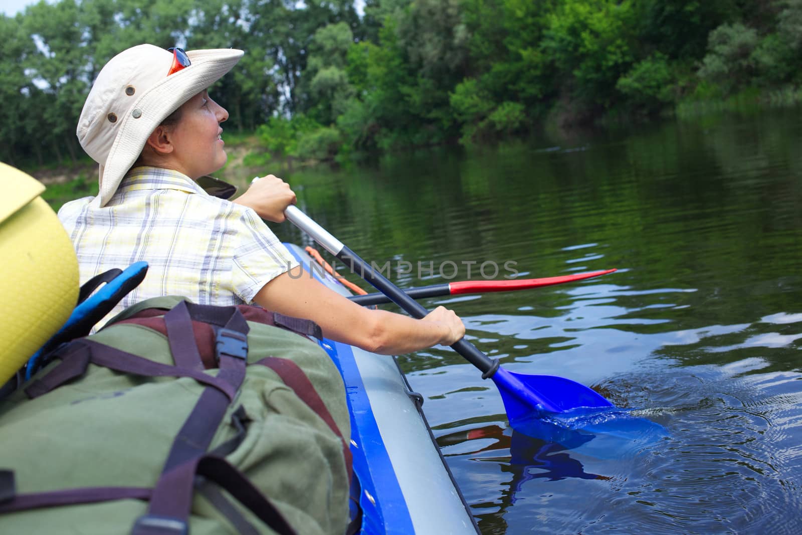 Back view of woman paddling a kayak on the river, enjoying a lovely summer day