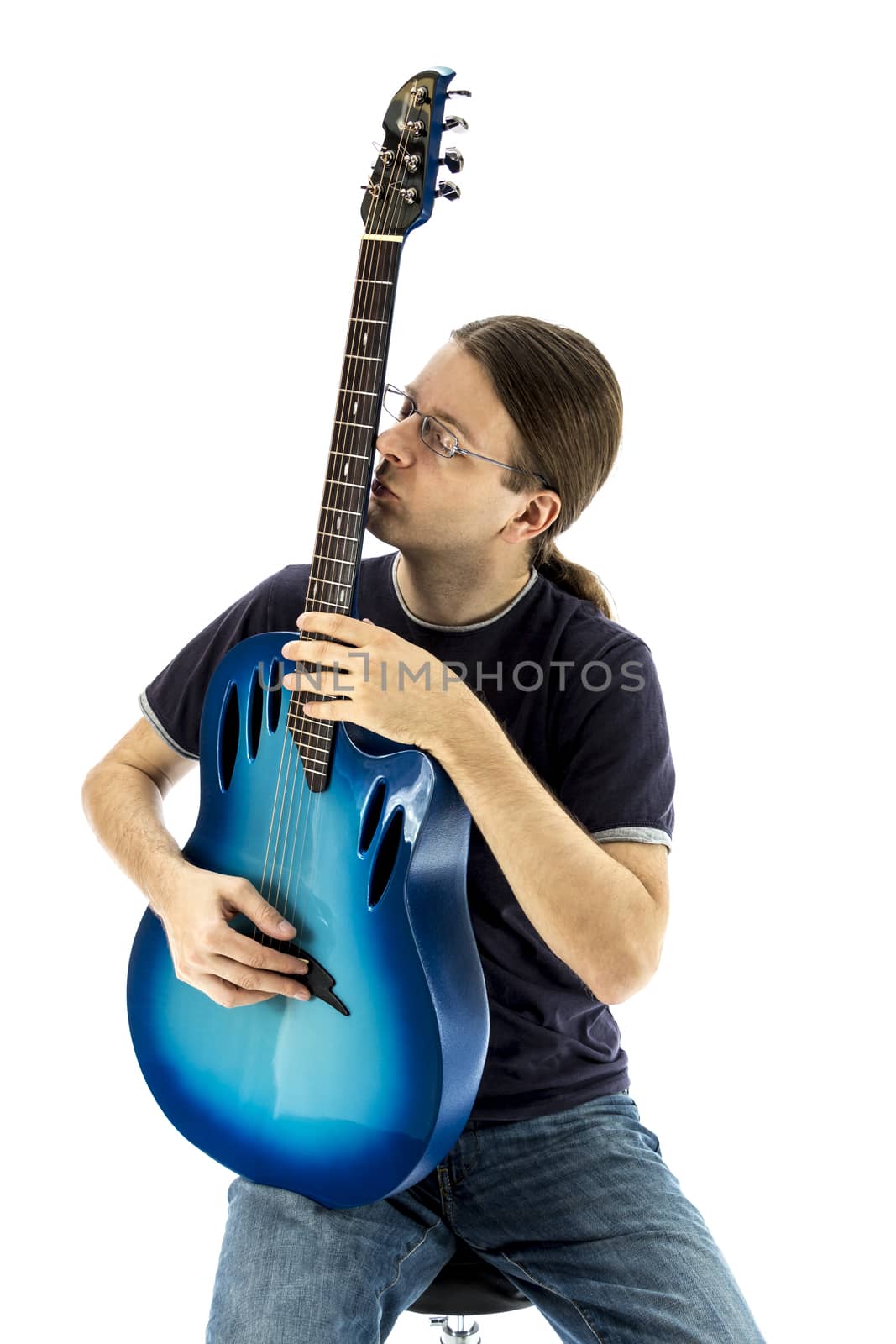 Young guitarist sitting straight and kissing his electric guitar