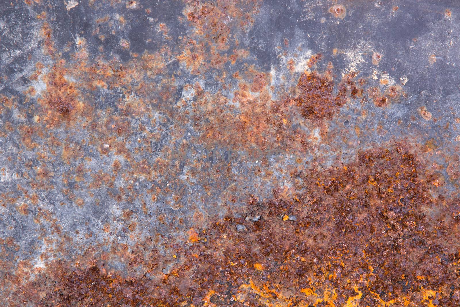 Grungy old rusting metal surface with pitted flaking blue paint and red ferric oxides or corroded rust caused by moisture and weathering, background texture