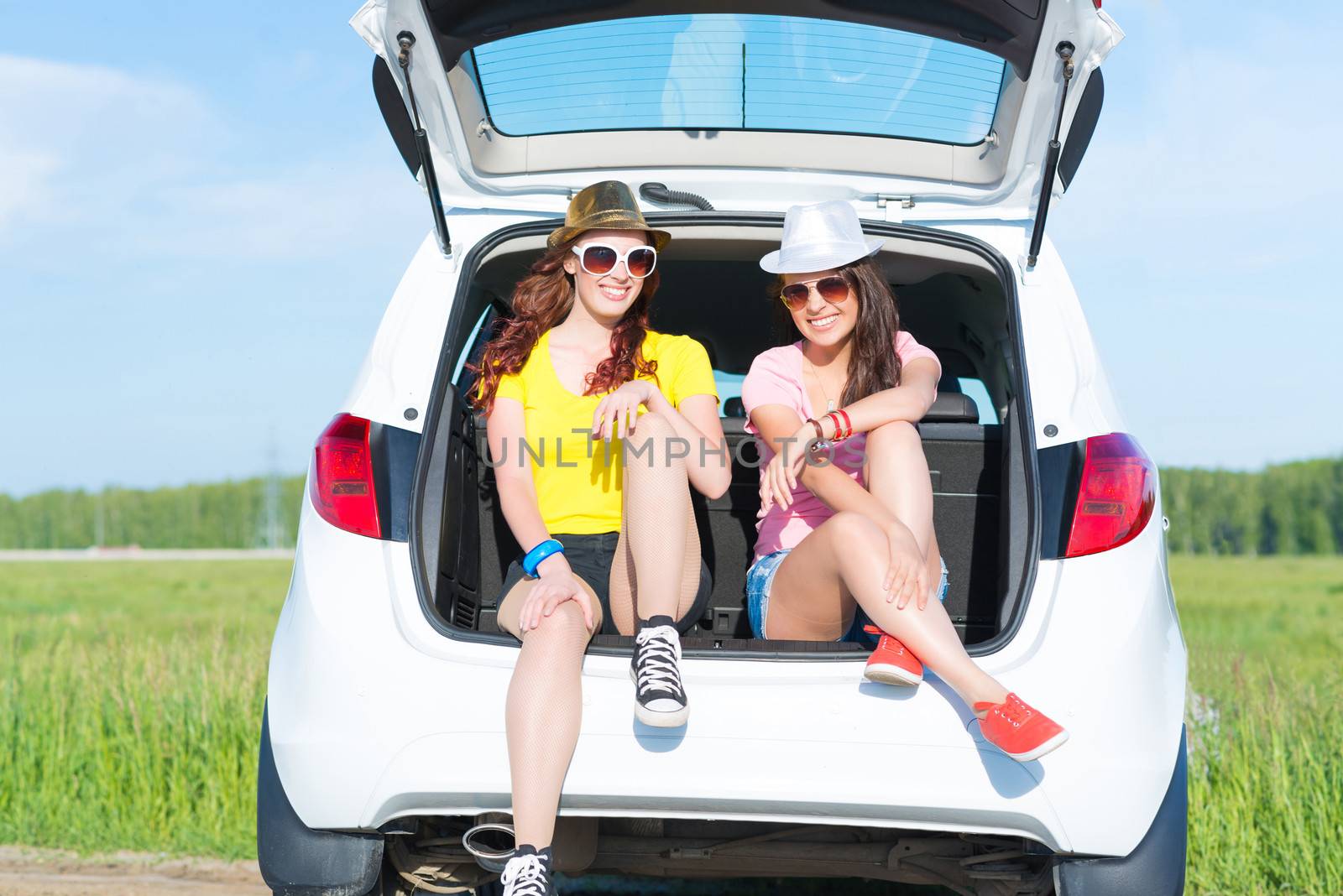 young attractive woman sitting in the open trunk of a new car, a summer road trip