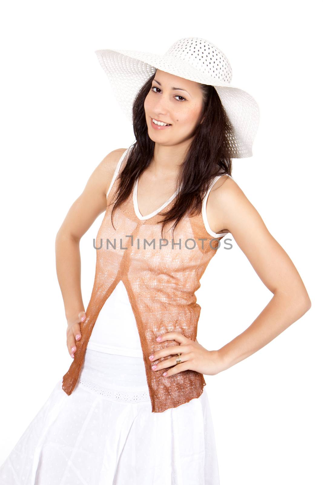 Brunette woman in white sun hat in a white dress, on white background, posing with hands on hips