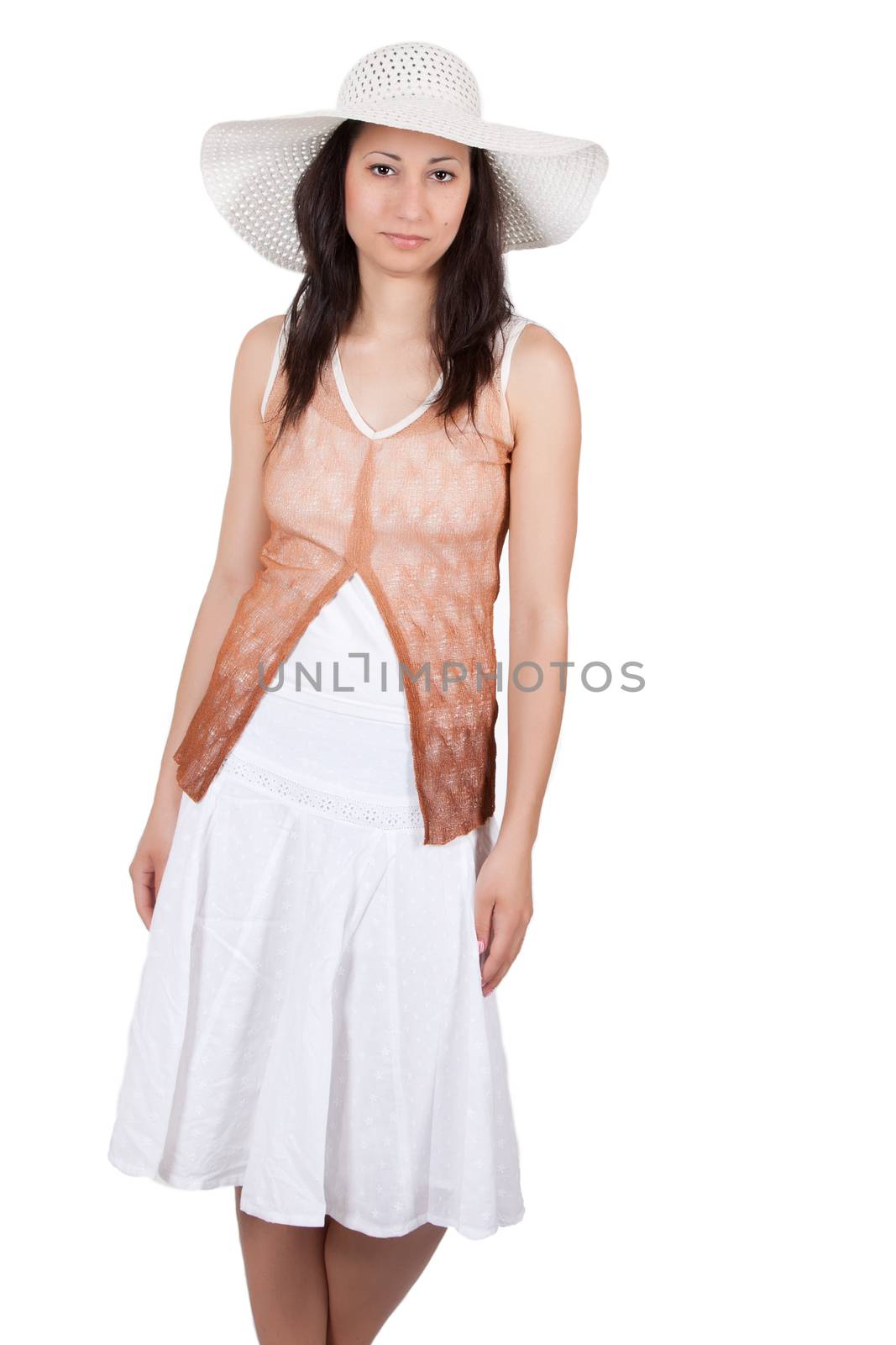 Brunette woman in white sun hat in a white dress, on white background, posing like a model