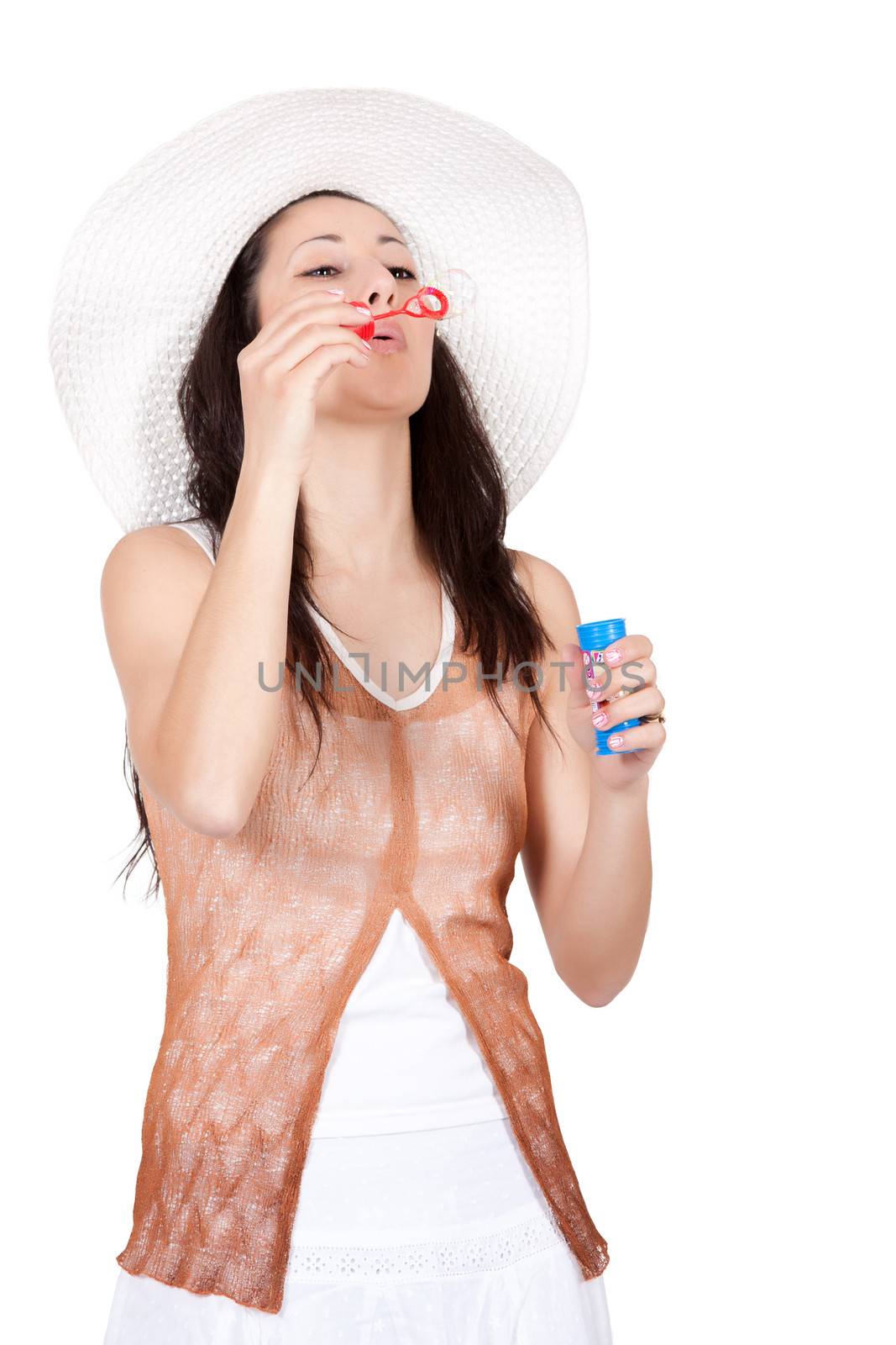 Brunette woman in white sun hat in a white dress, on white background, blowing and makes soap bubble