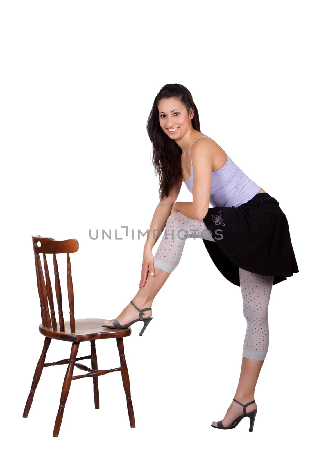 Long-haired brunette woman has landed a leg on a chair, is a smiling, isolated on white background