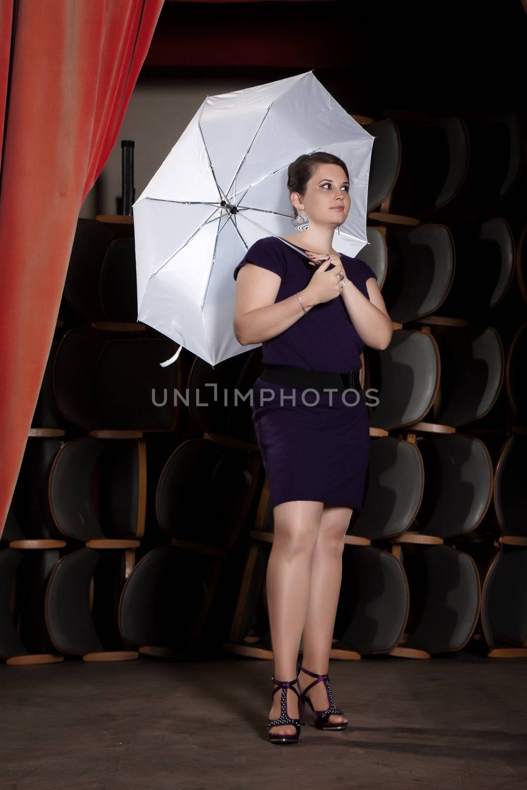 Female Actress in a purple dress with a white umbrella stand on the podium