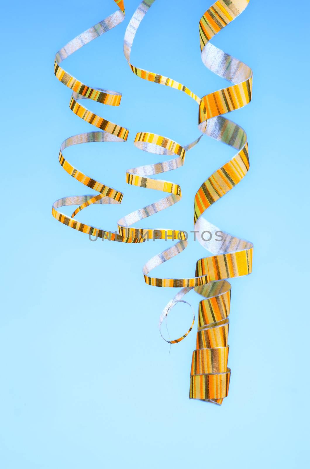 Three Yellow Striped Hanging Down Curled Party Streamers isolated on Blue background