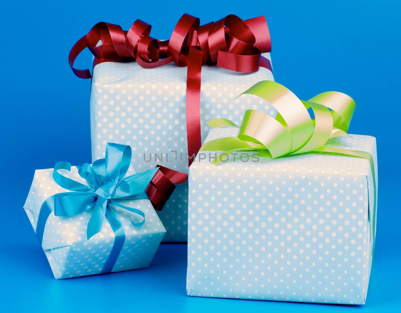 Arrangement of Three Gift Boxes with Ribbons and Bows isolated on Blue background