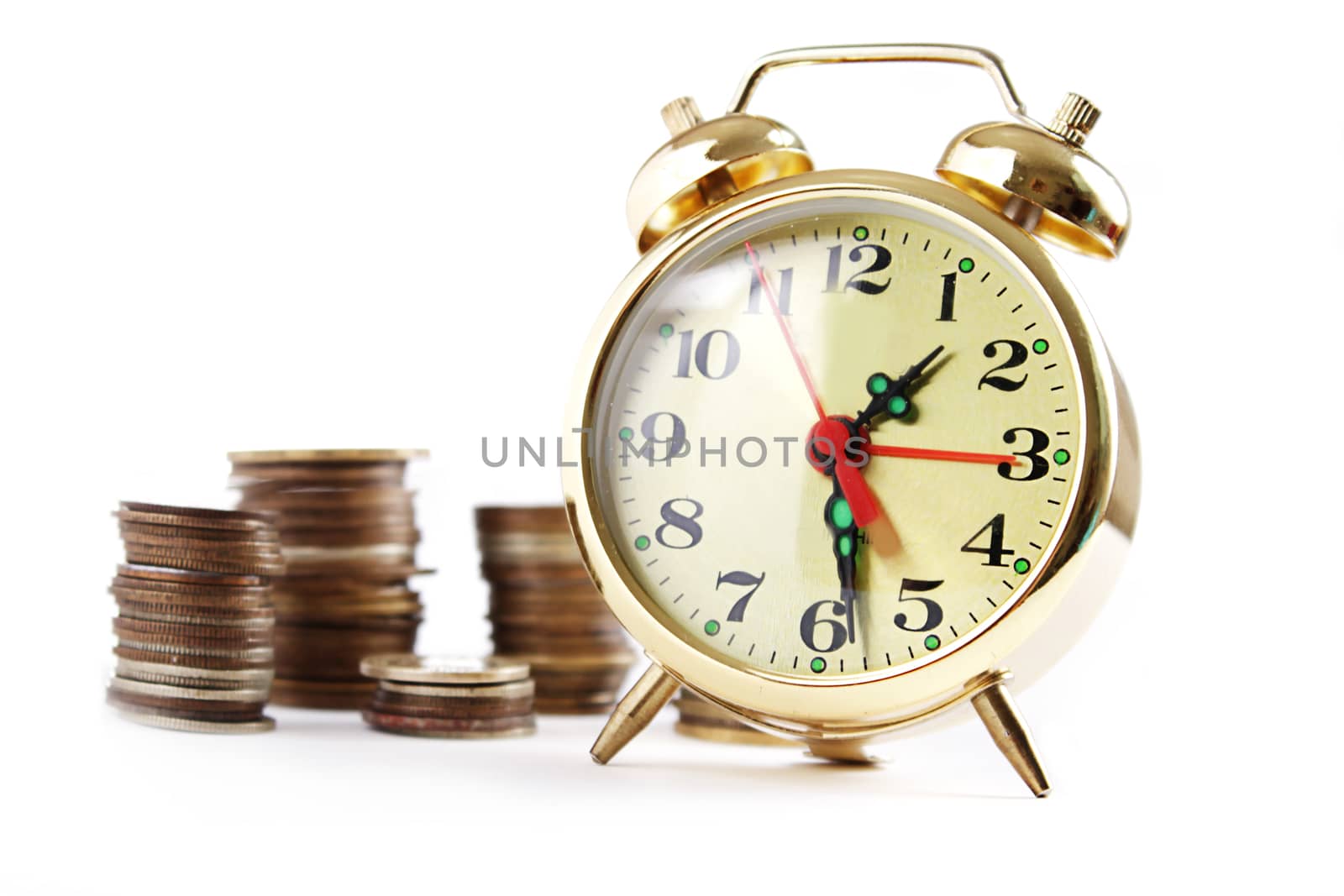 Alarm clock and coins in pile isolated on white, money concept
