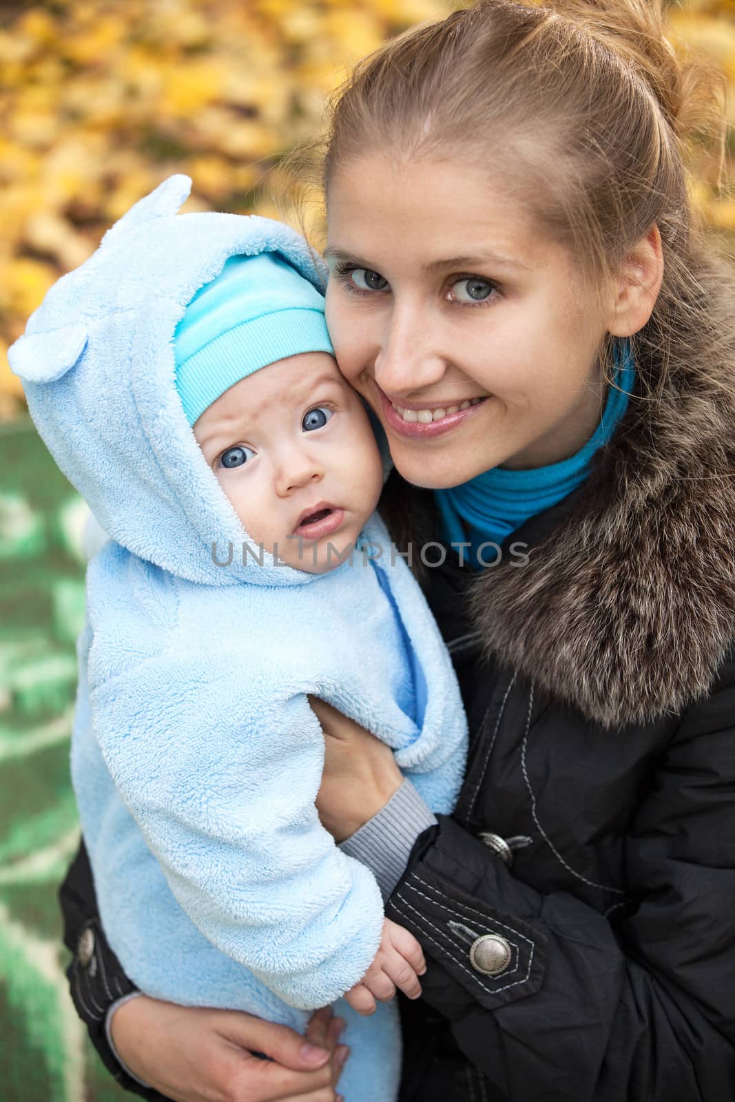 Portrait of young woman and her baby son in autumn park