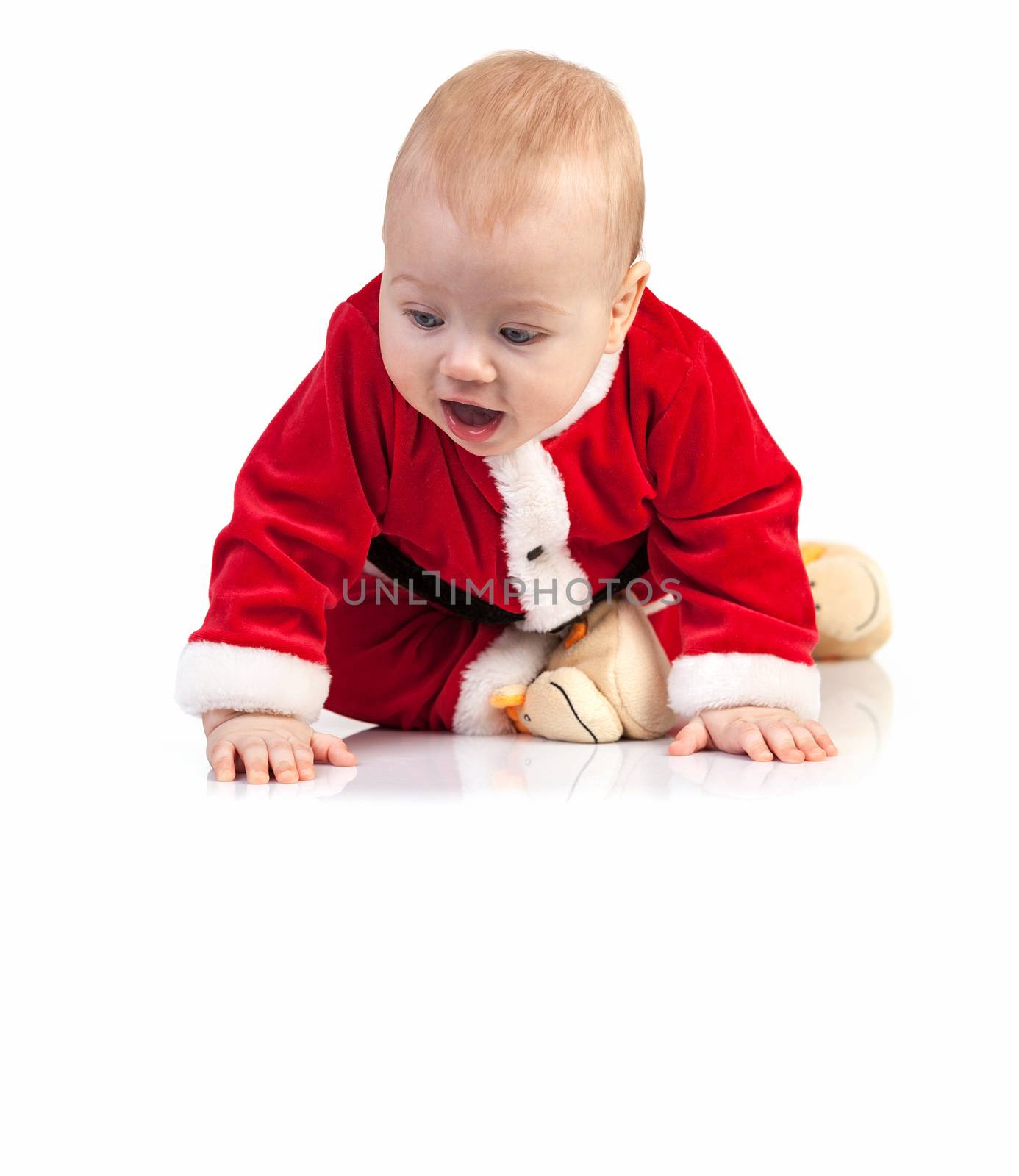 Cute little boy in Santa costume looking down on white background