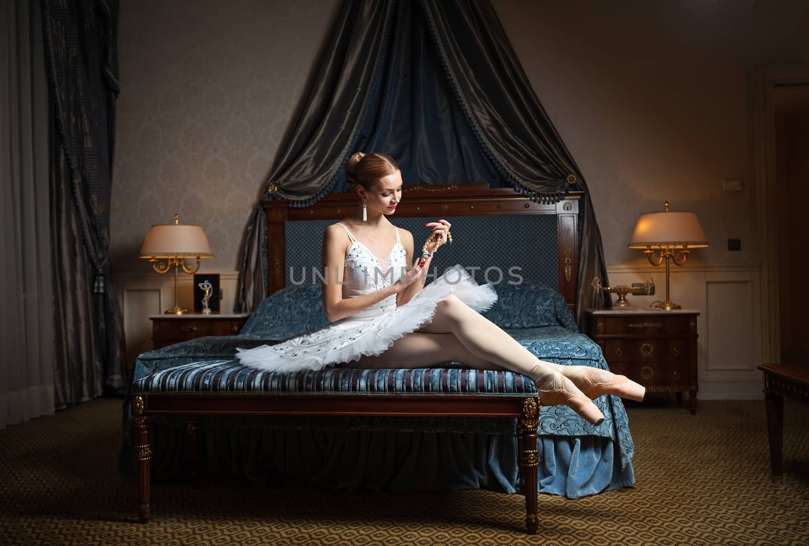 Ballet dancer in bedroom holding pearl necklace by photobac
