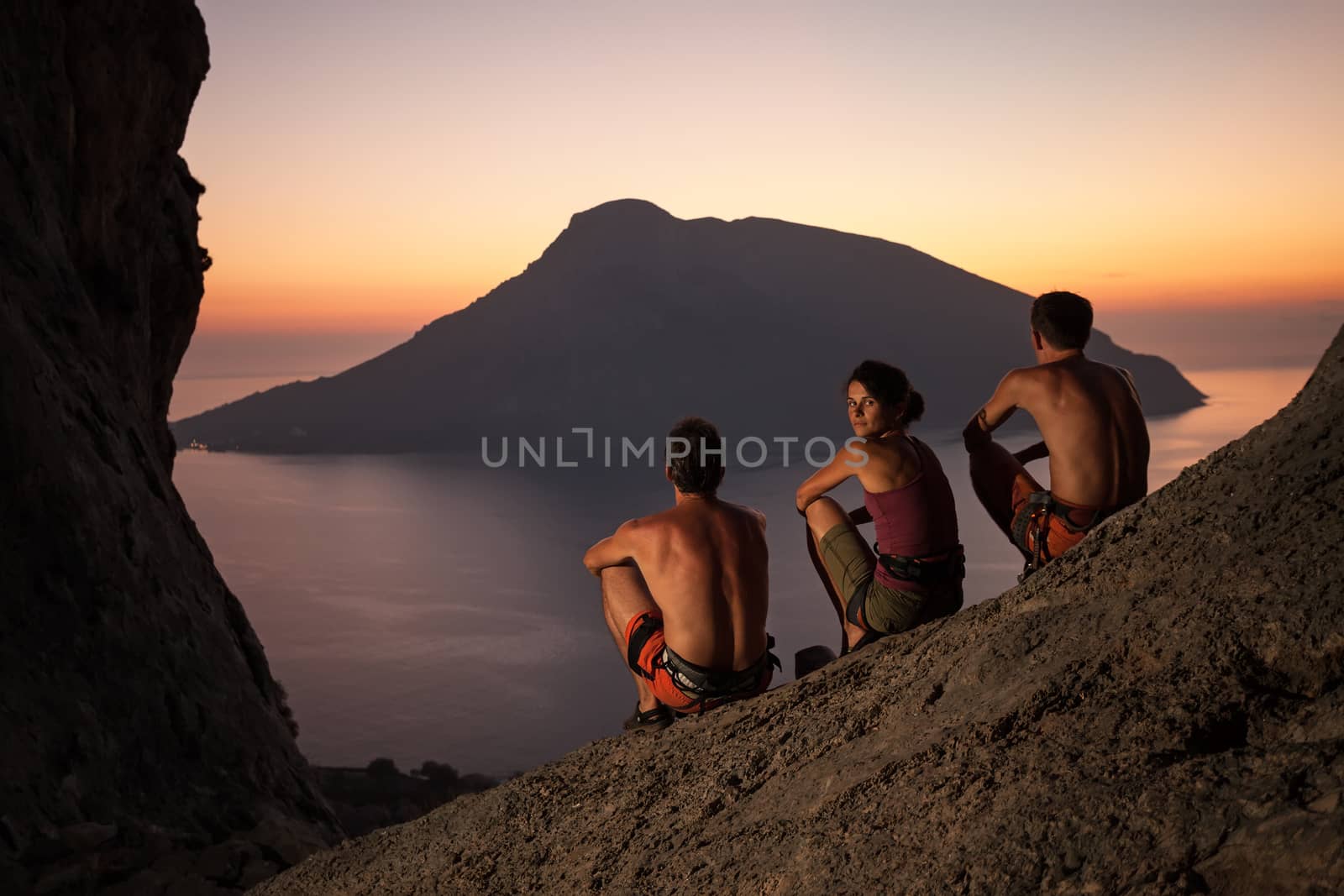 Three rock climbers having rest and watching sunset