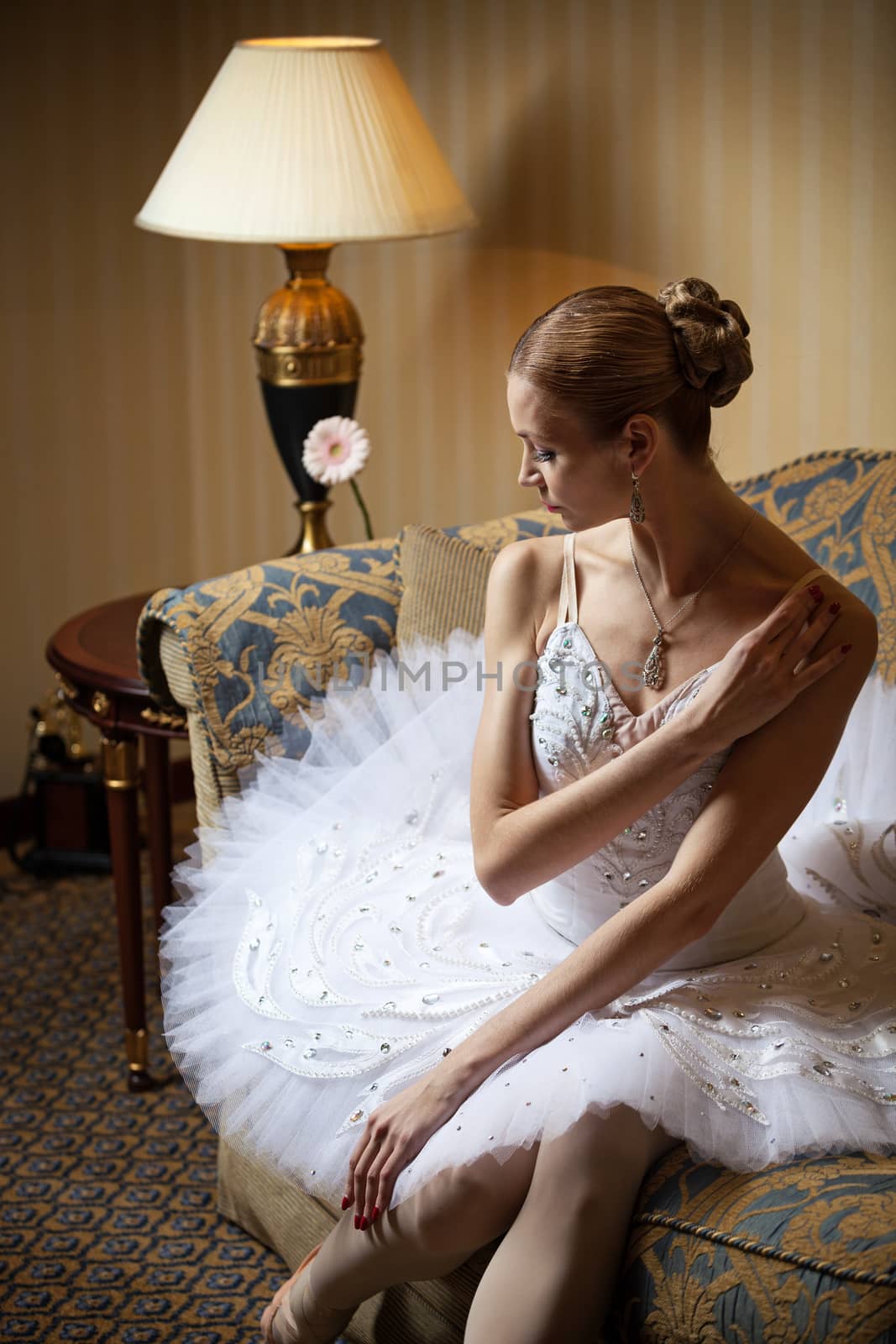 Professional ballet dancer sitting on sofa and looking down