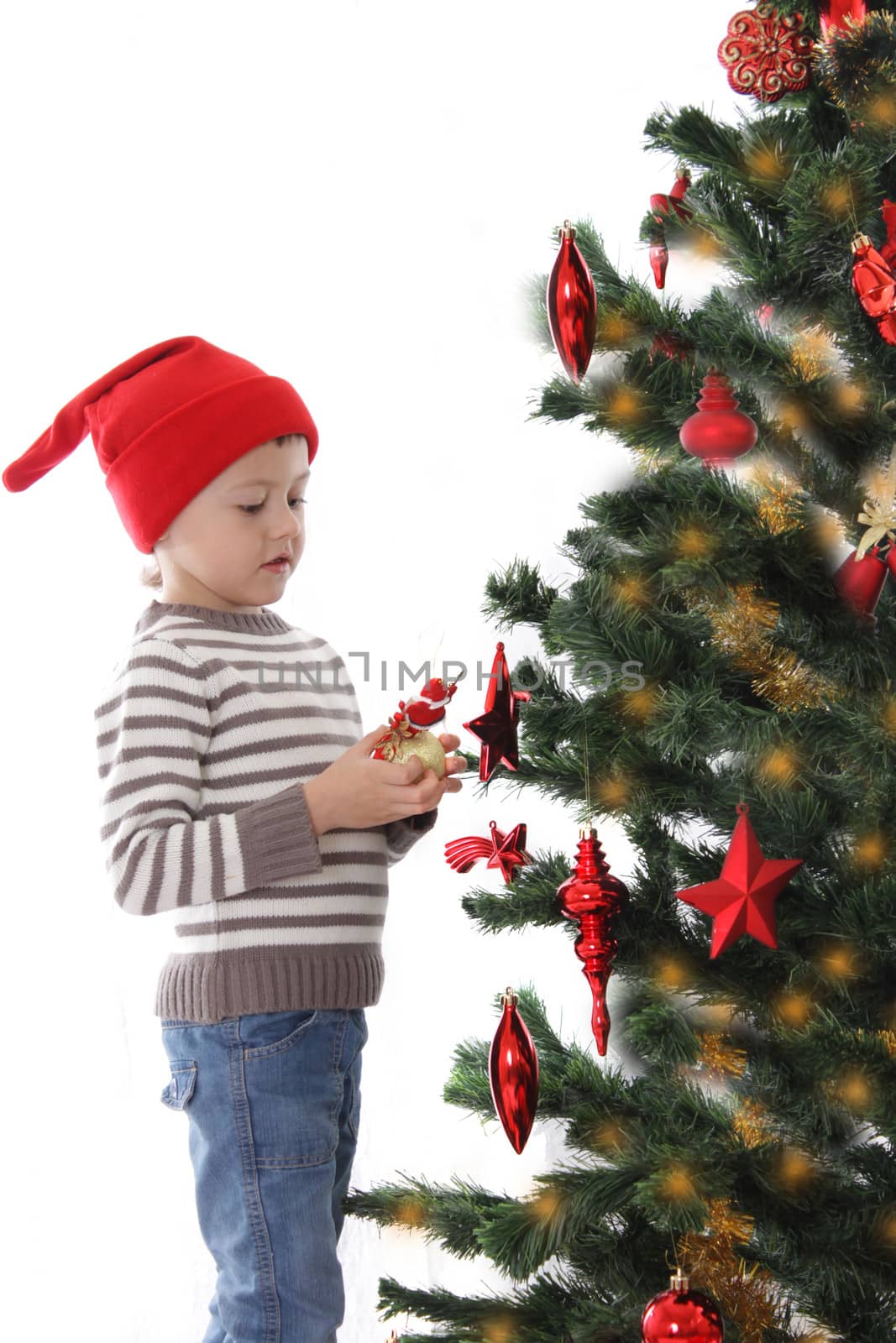 Boy in Santa hat decorating Christmas tree isolated on white