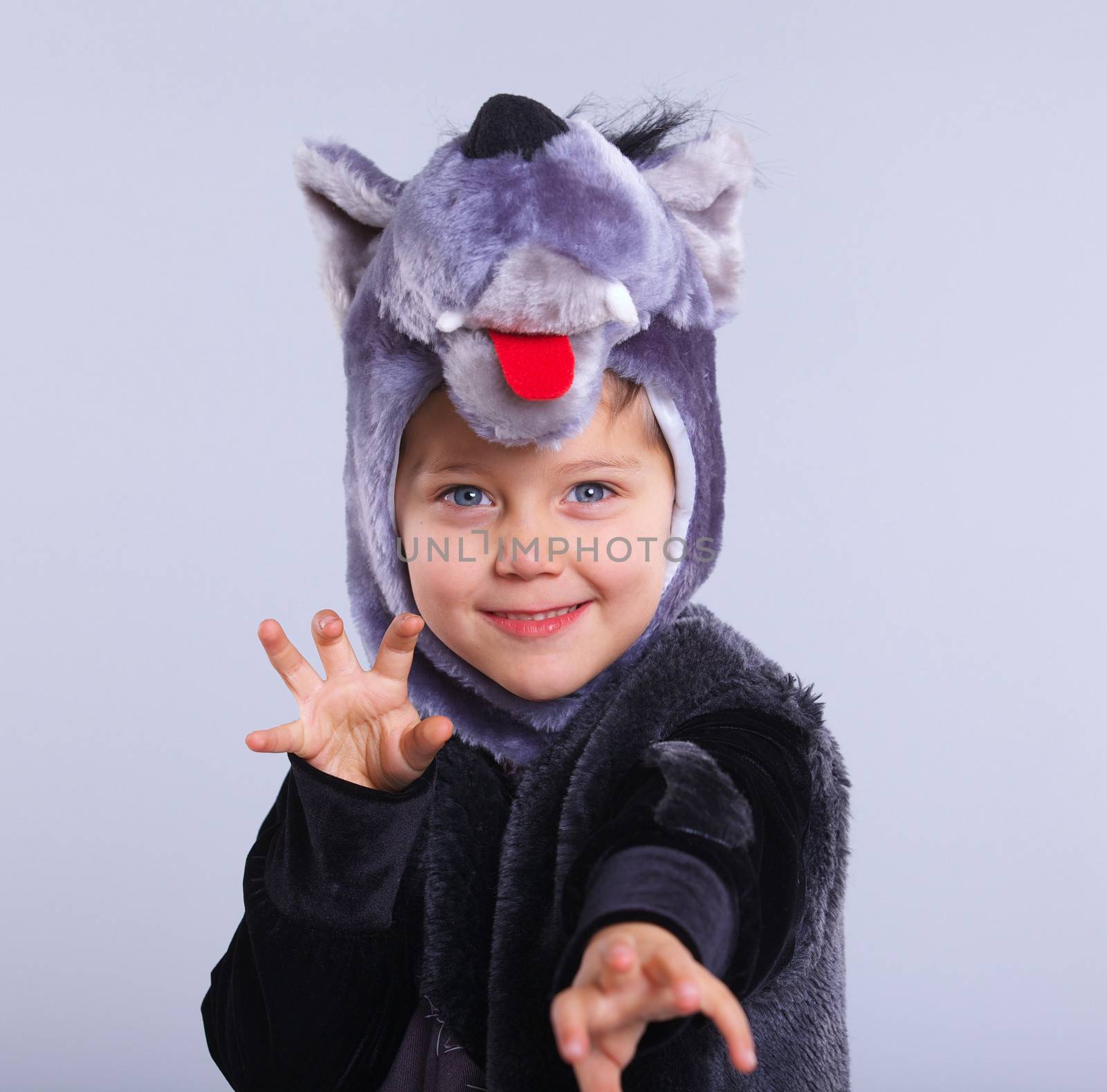 A portrait of a little boy trying a carnival suit of wolf on the grey background