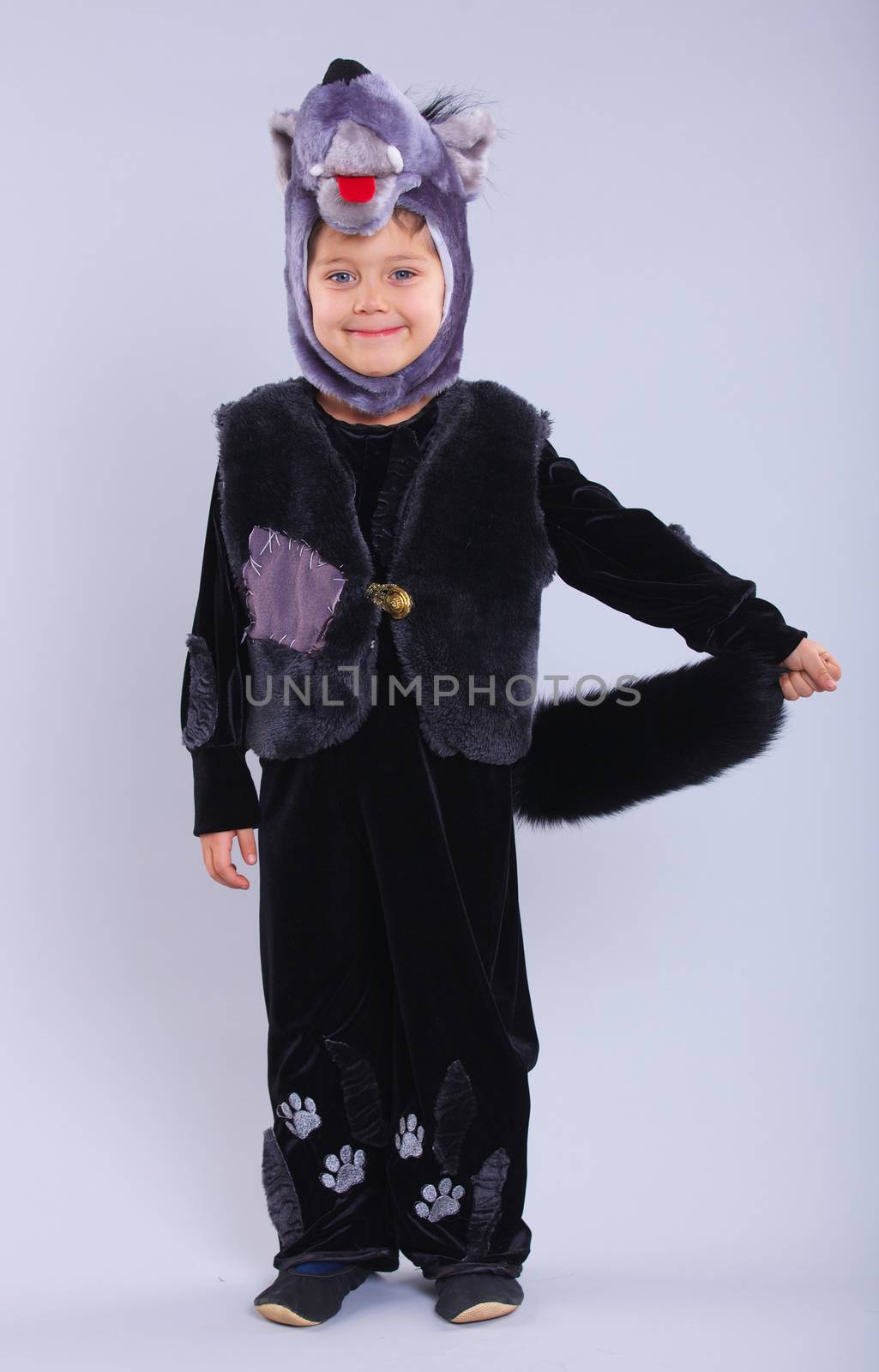Little boy trying a carnival suit of wolf on the grey background