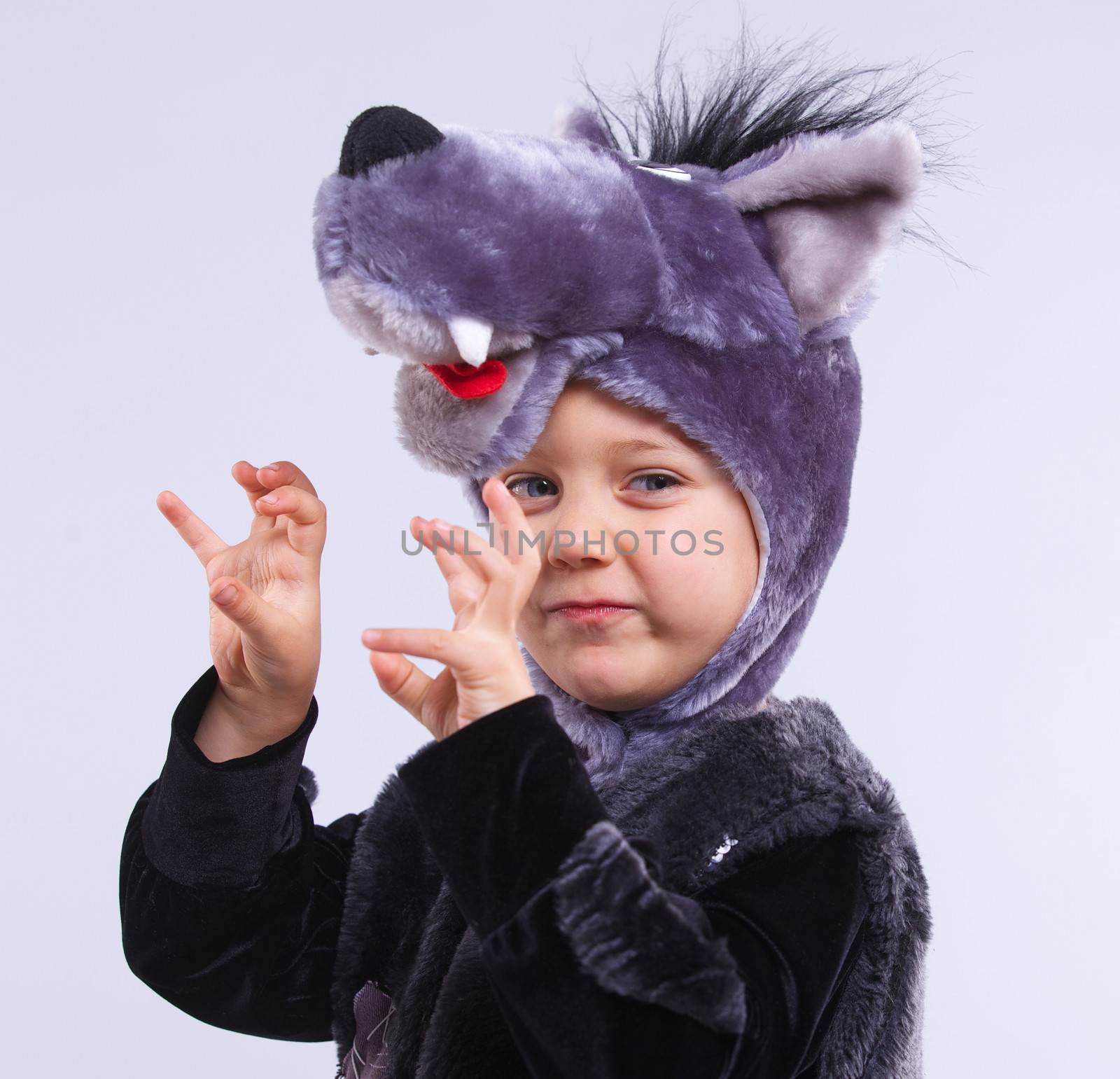 A portrait of a little boy trying a carnival suit of wolf on the grey background