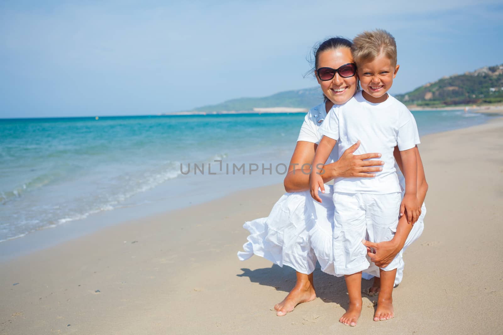 Mother and son having fun on the beach by maxoliki