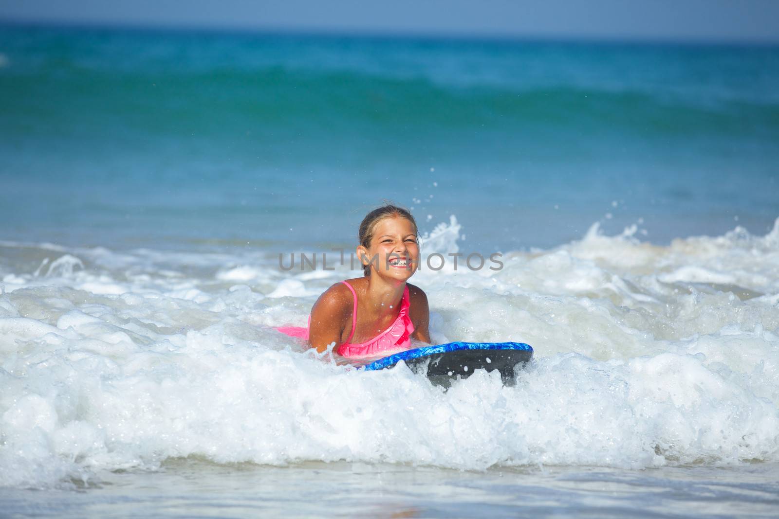 Summer vacation - Happy cute girl having fun with surfboard in the ocean