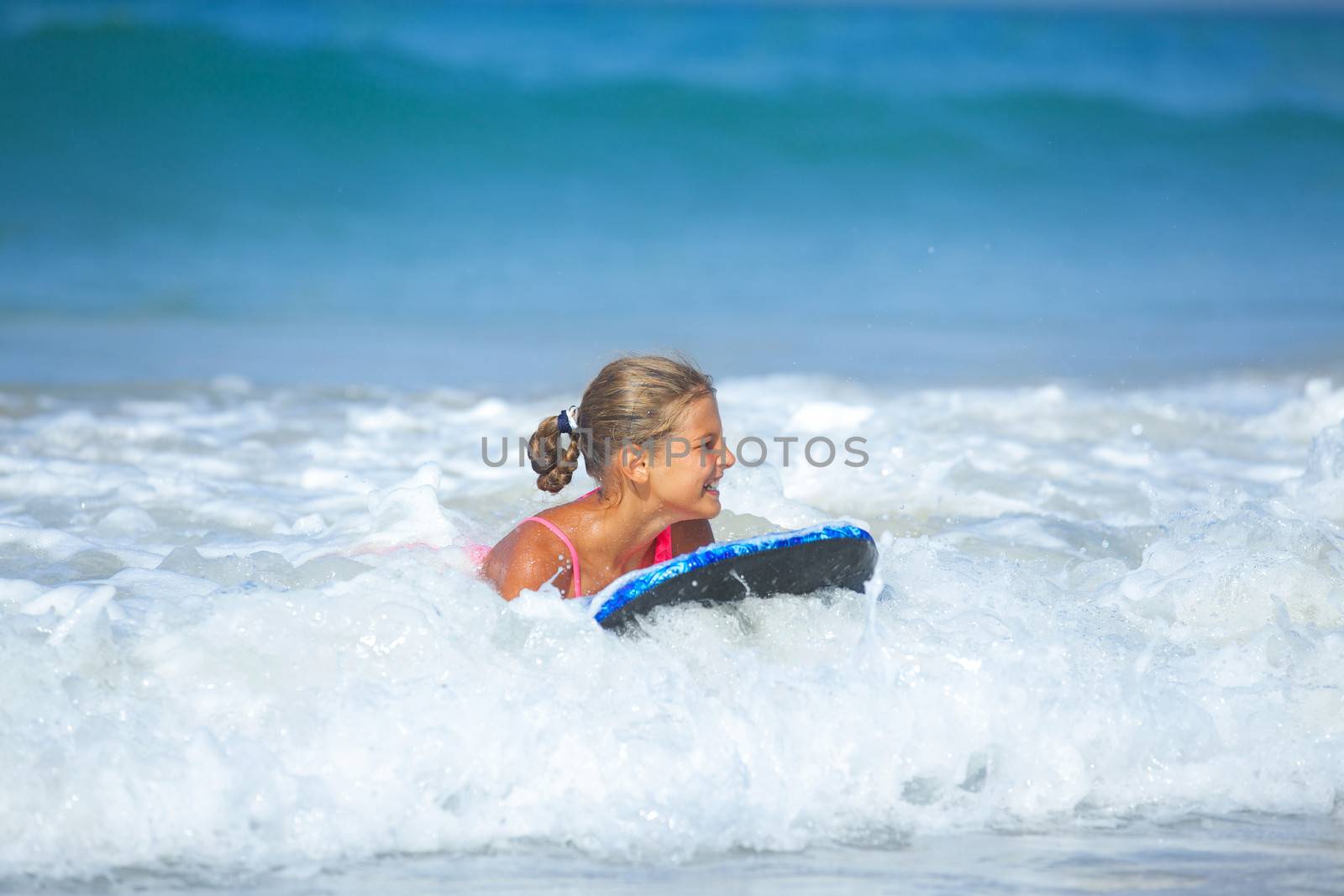 Summer vacation - Happy cute girl having fun with surfboard in the ocean