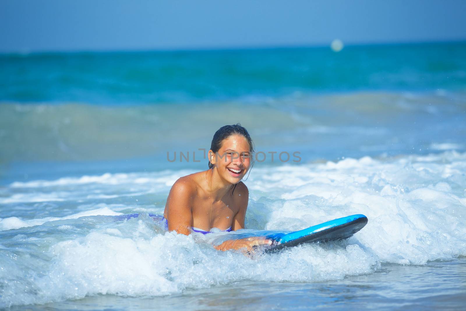 Summer vacation - Happy cute girl having fun with surfboard in the ocean