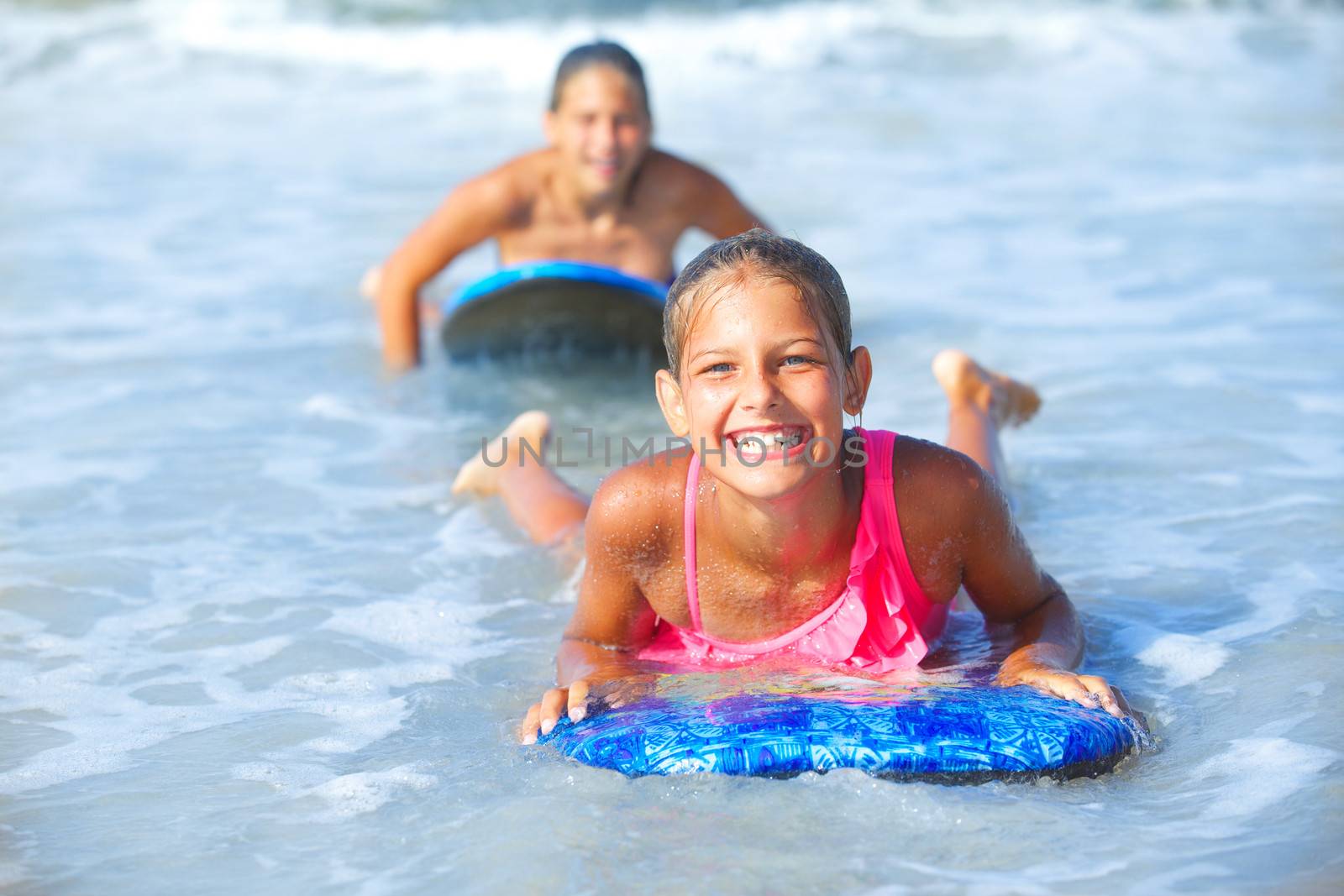 Summer vacation - Two cute girls having fun with surfboard in the ocean