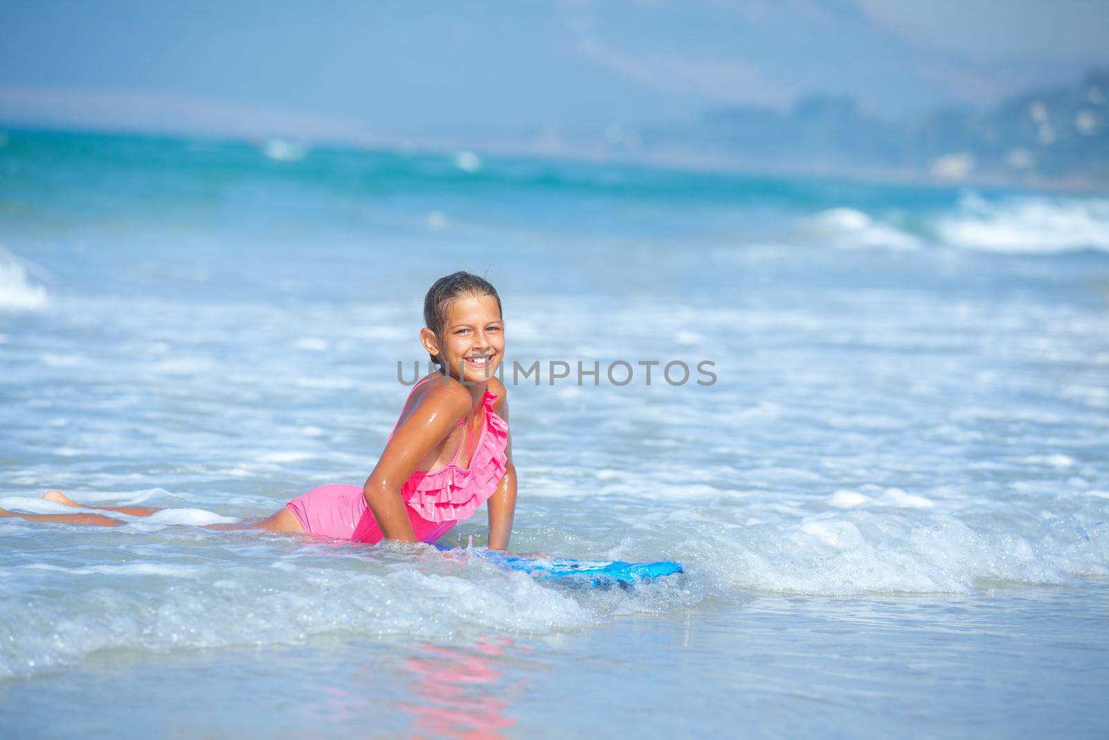 Summer vacation - Happy cute girl having fun with surfboard in the ocean