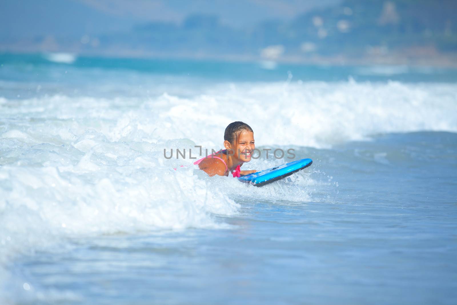 Summer vacation - Happy cute girl having fun with surfboard in the ocean