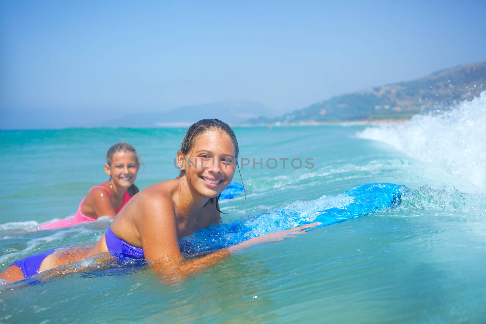 Summer vacation - Two cute girls having fun with surfboard in the ocean