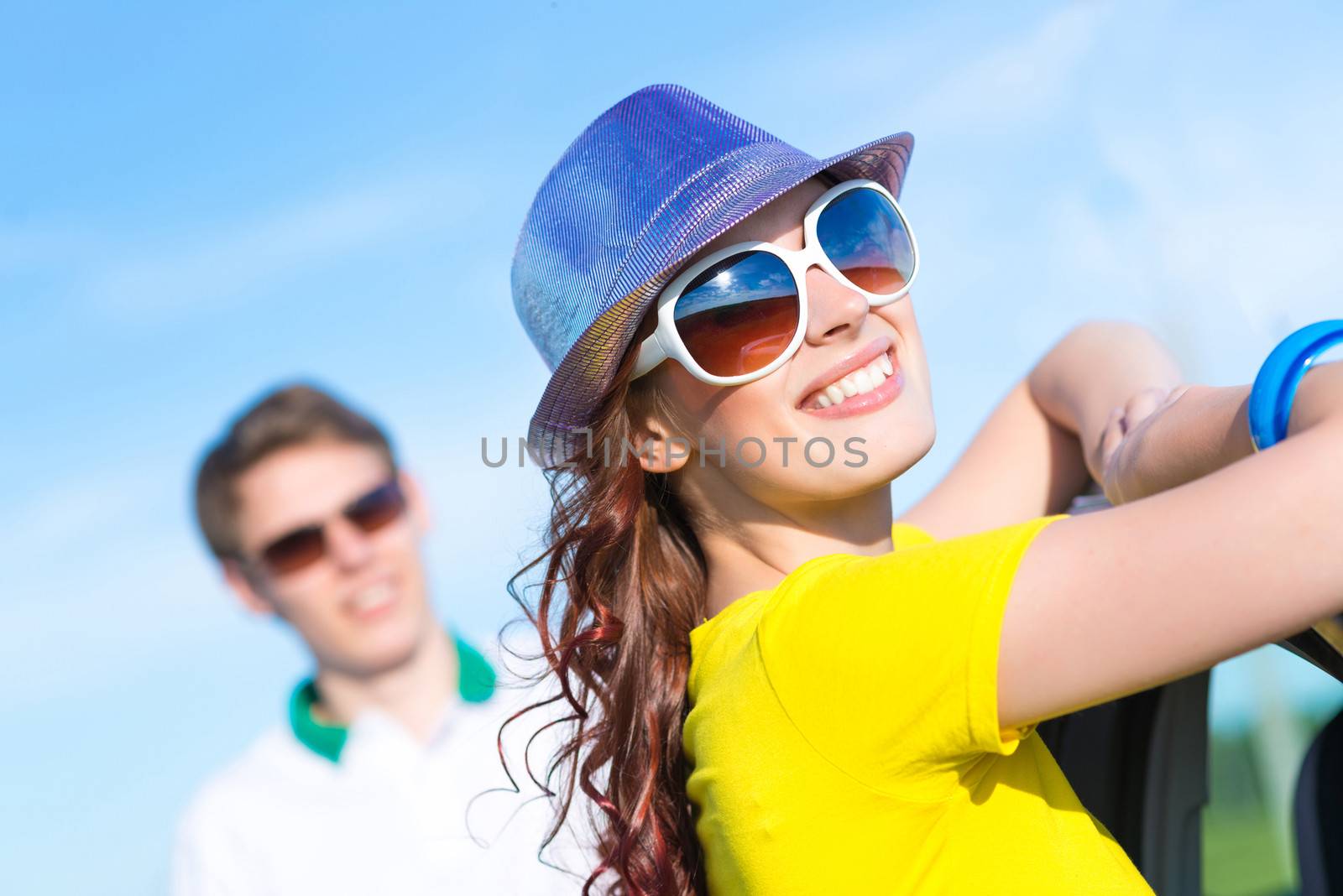 young attractive woman in sunglasses and hat stands next to a car, a close-up portrait