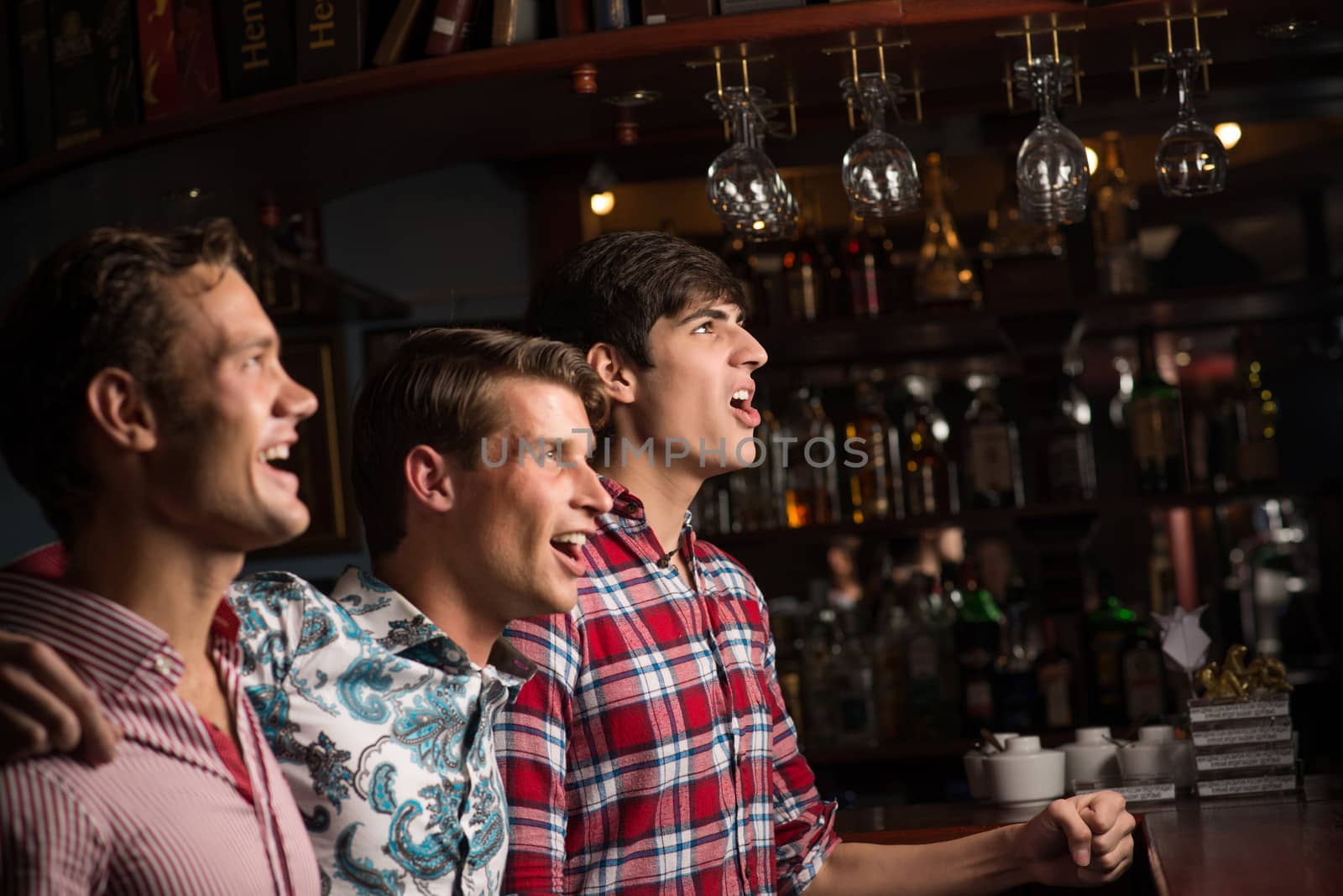 Three men stand in a row embracing smile and look in front of you, sports fans