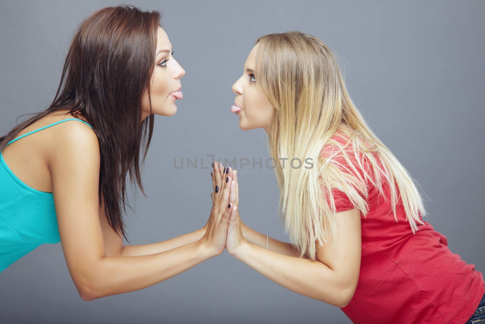 Relation between two playful girls putting out their tongues